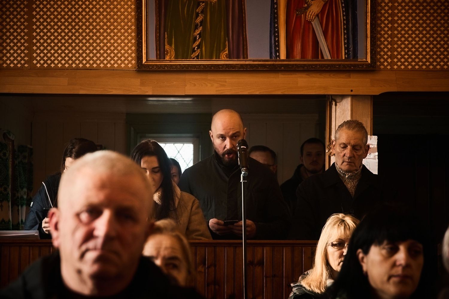 Dark wooden church interior with decorative lattice panels and religious icons on display.