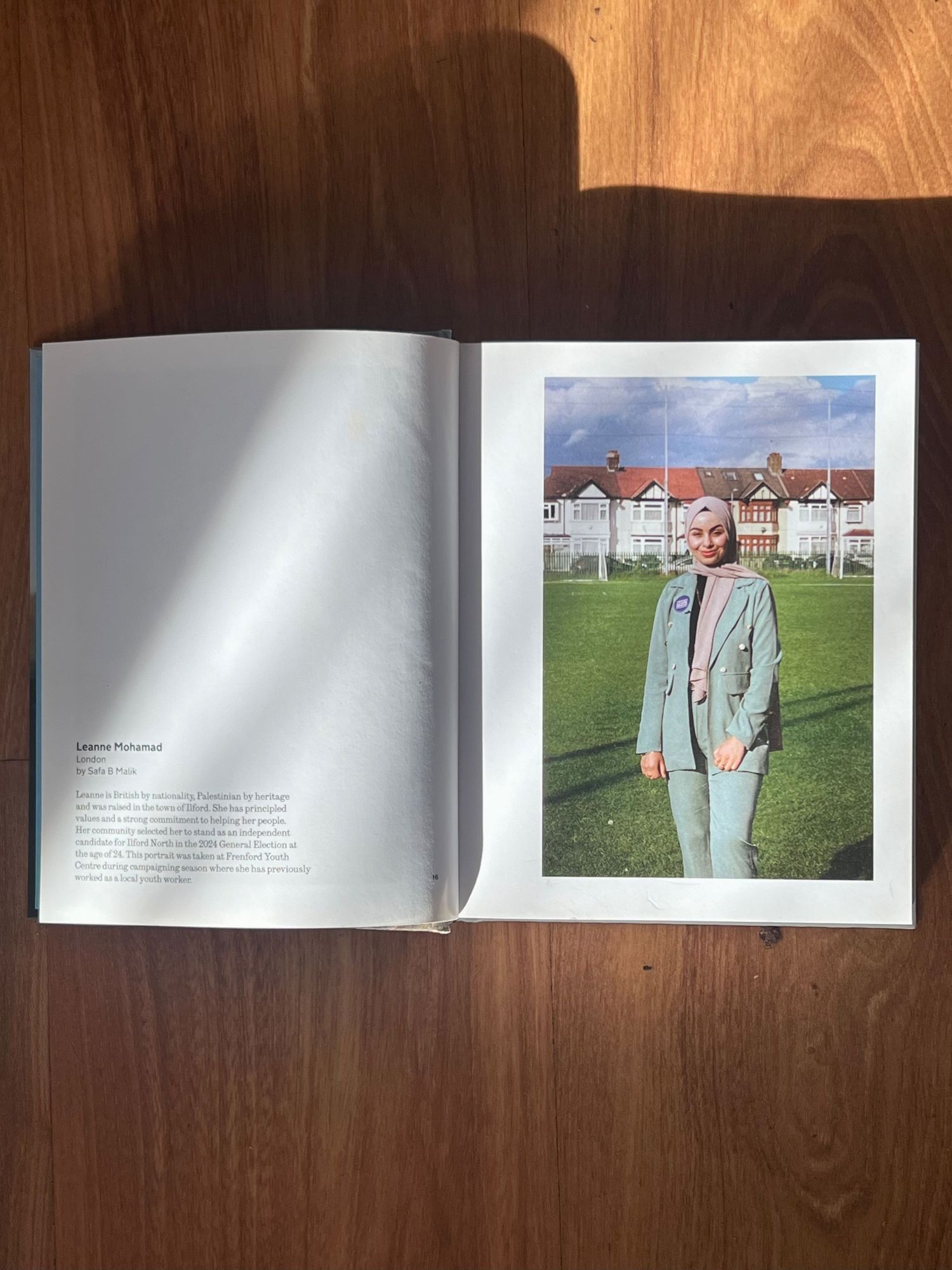 Pages of a photography book spread open on a wooden table showing minimalist fashion portraits and text layouts.