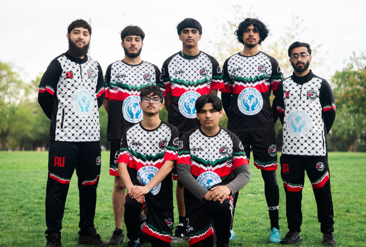 Soccer team poses in two rows wearing distinctive black and white patterned uniforms.