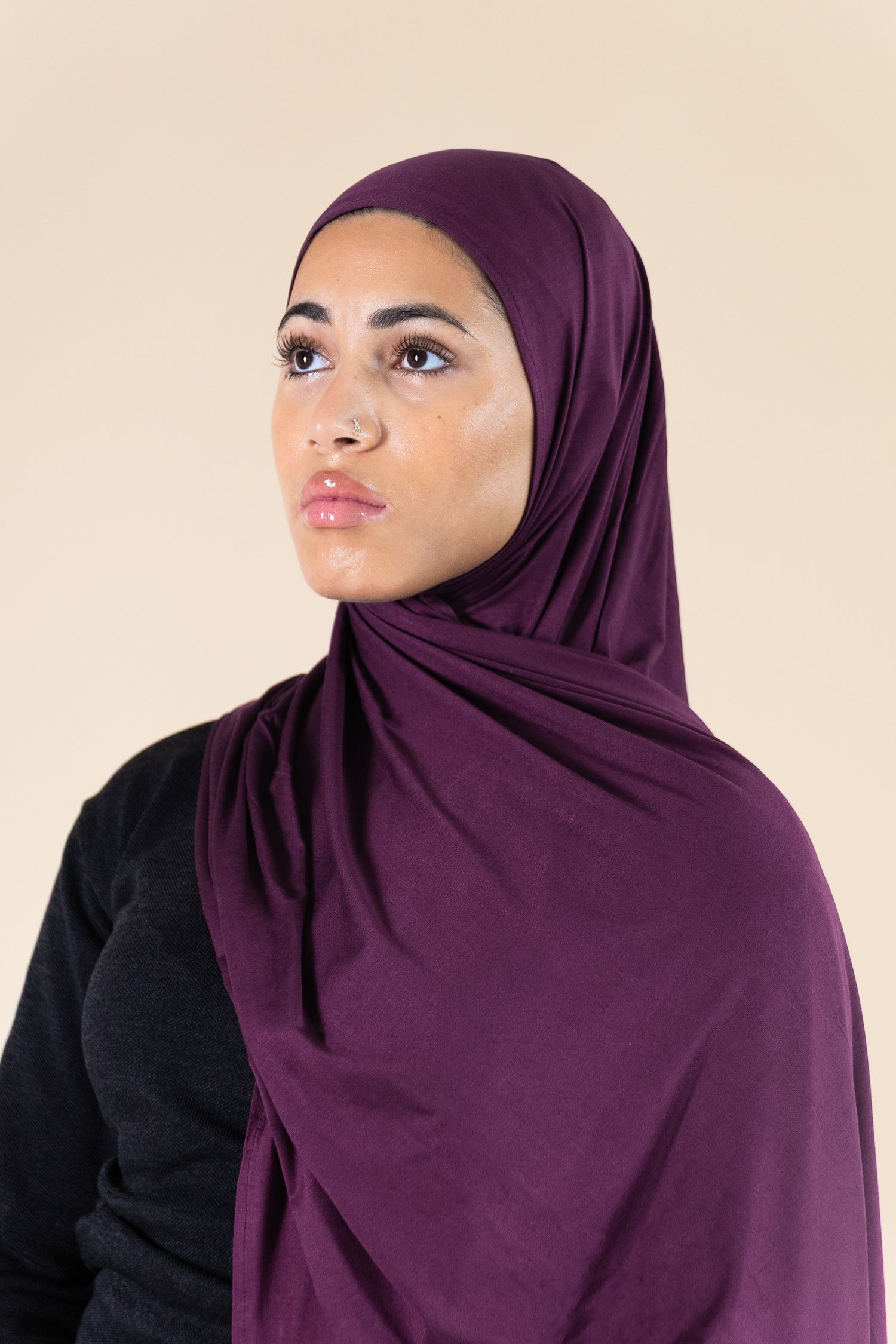 A series of profile views showing a person wearing a deep purple hijab and black top against a light background.