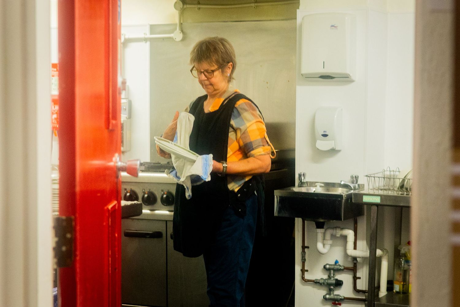 A person works behind a counter in a bright red-accented kitchen area.