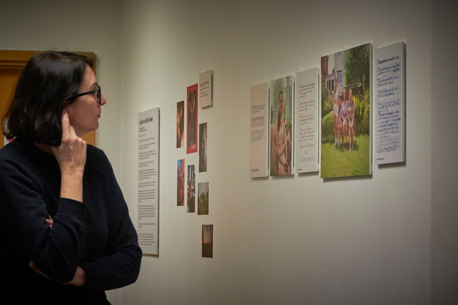 Person views art exhibition with framed photographs and text displayed on a white gallery wall.