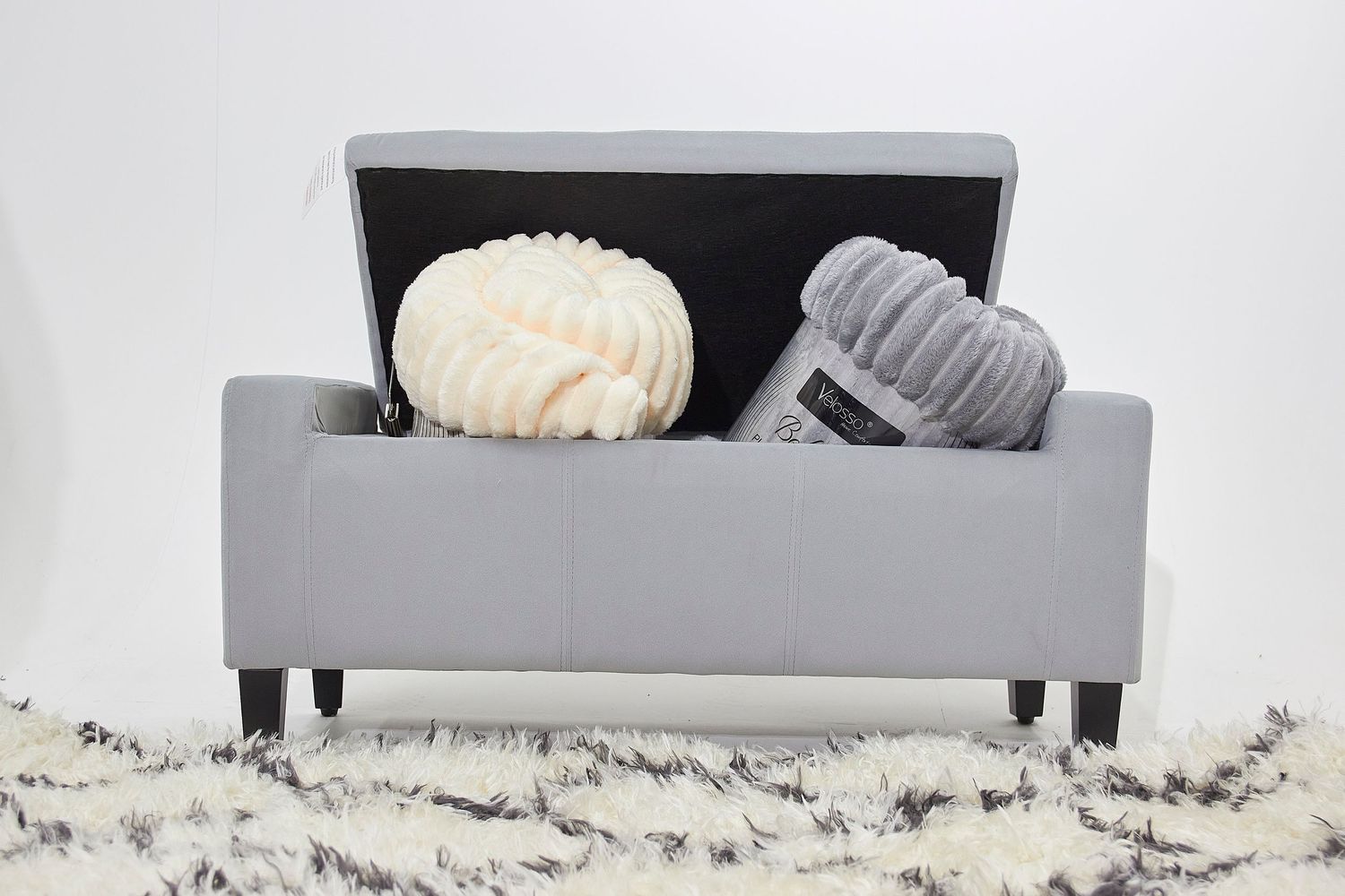 Modern fabric sofa with decorative pillows and blanket sits on a bright marble floor against white walls.