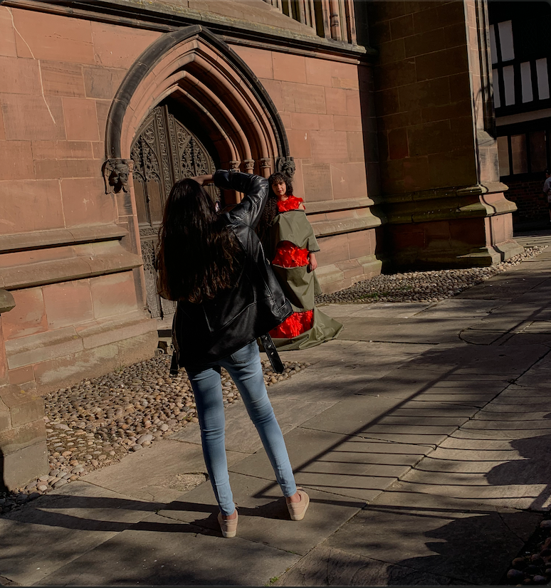 Woman with large backpack photographing ornate Gothic church doorway on sunny day.