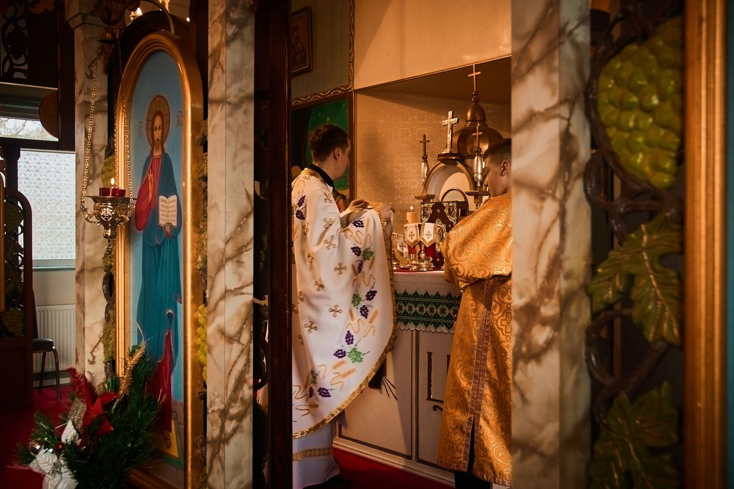 Orthodox church interior with decorative columns and religious artwork displayed on walls.