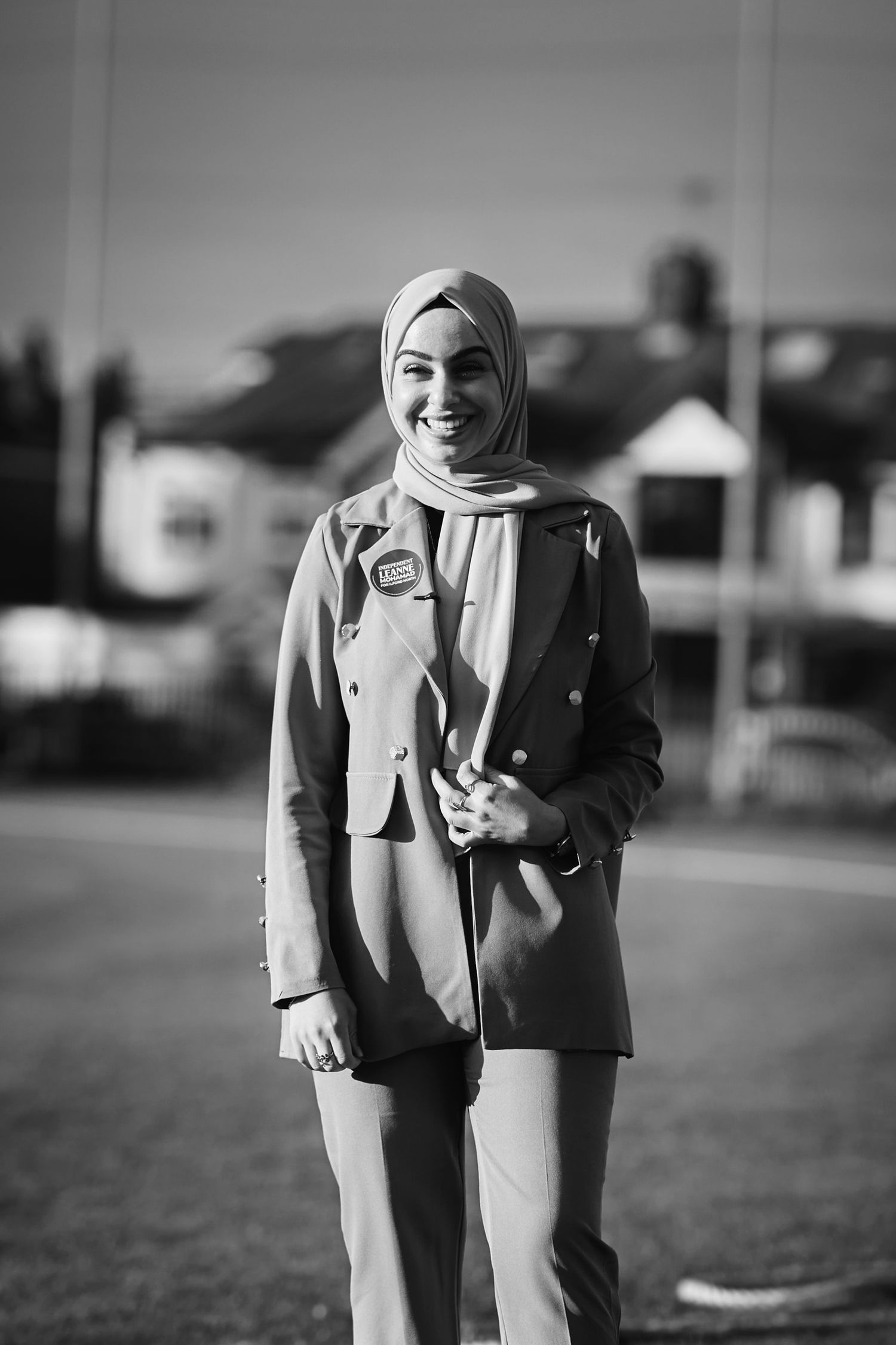 Black and white photo of someone in business attire standing on outdoor field.