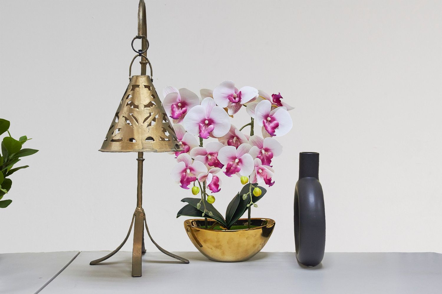 Decorative brass table lamps paired with pink orchids and vases create an elegant home decor vignette.