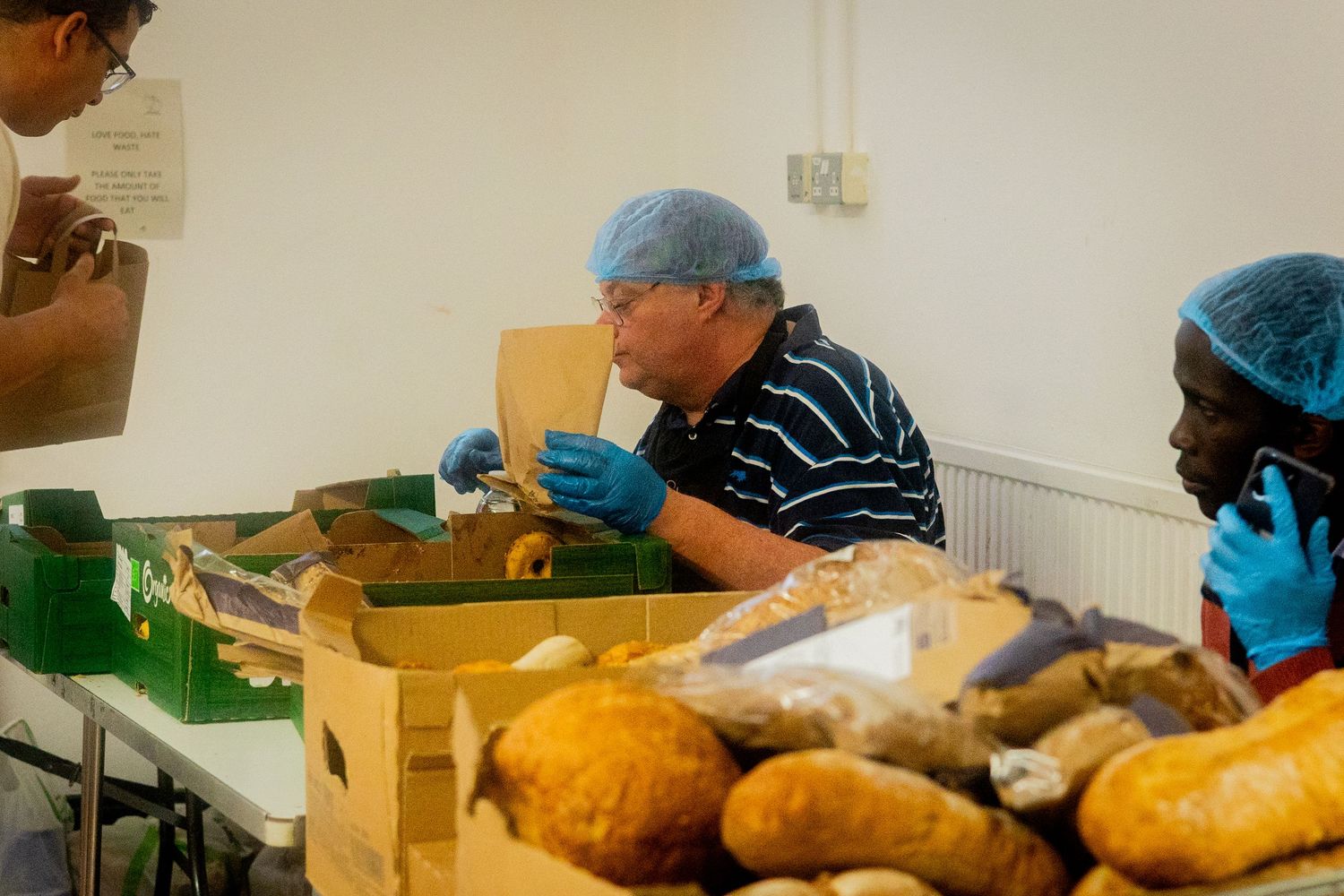 People working at tables preparing food in a community kitchen setting.