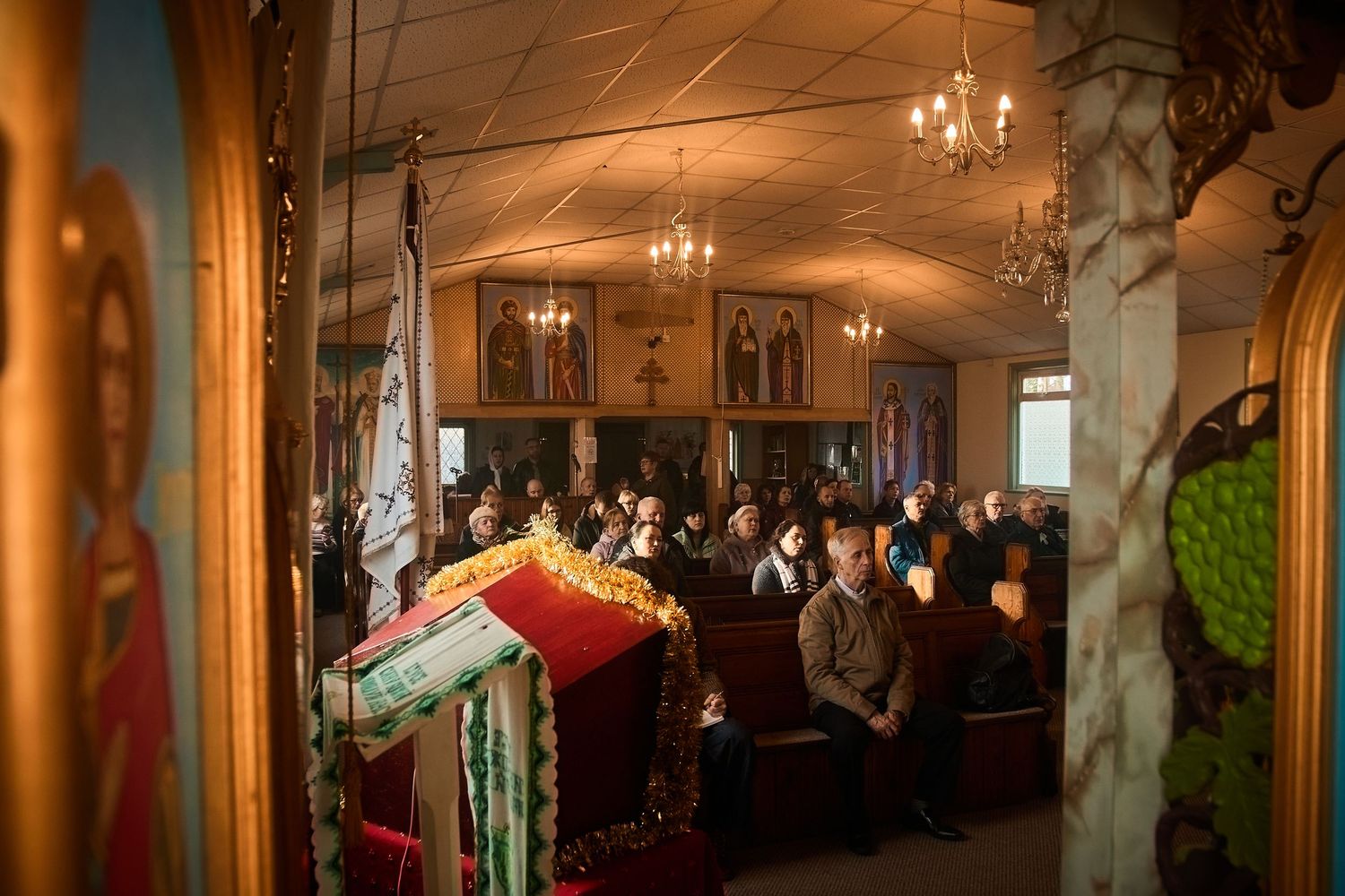 Panoramic view of an Orthodox church interior with hanging chandeliers and religious artwork.