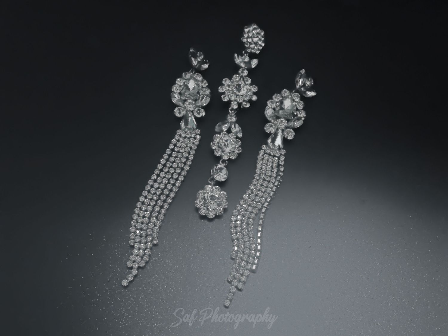 Wedding jewelry set with dangling crystal earrings and floral hair pieces displayed on dark background.