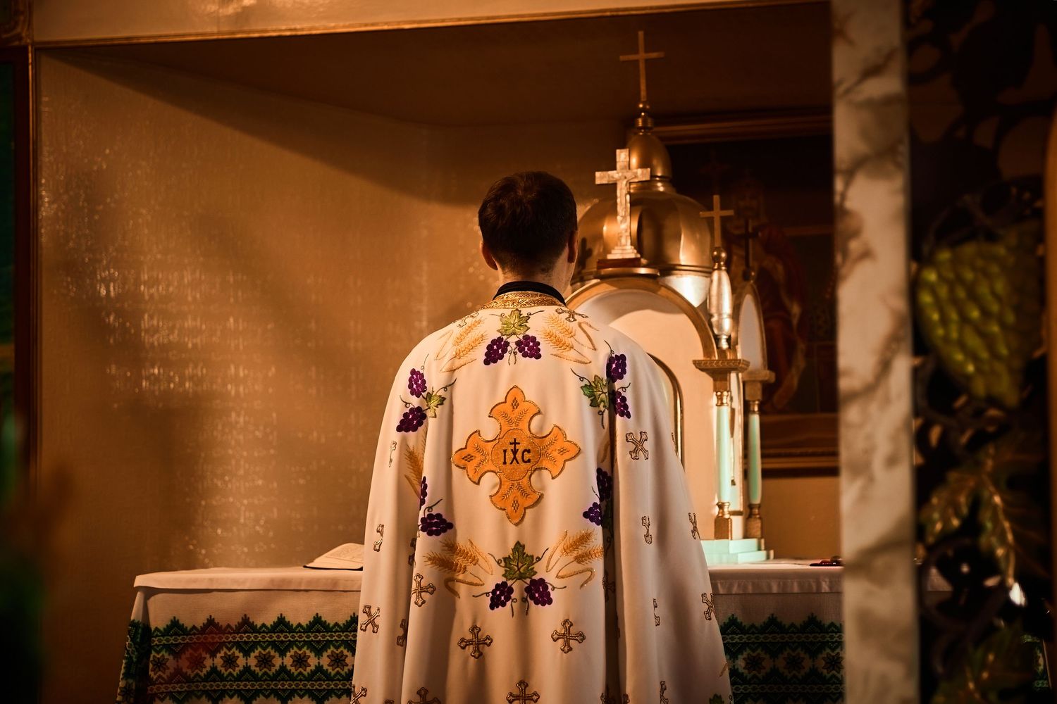 Ornate gold religious vestments with cross designs illuminated by candlelight during a church service.