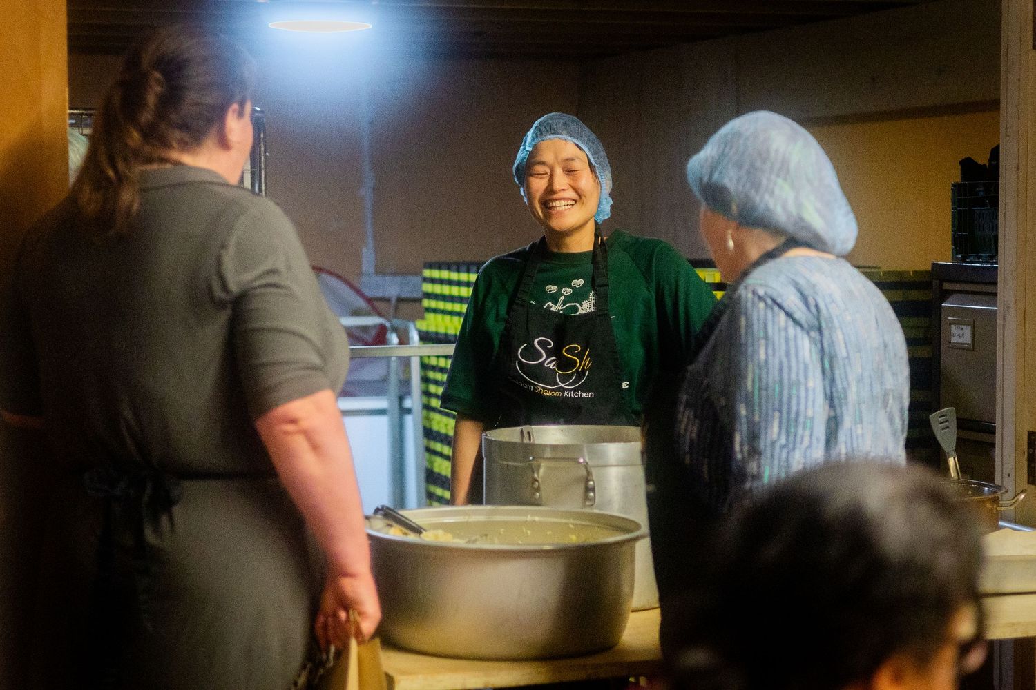 Kitchen staff working together in a dimly lit commercial kitchen setting.