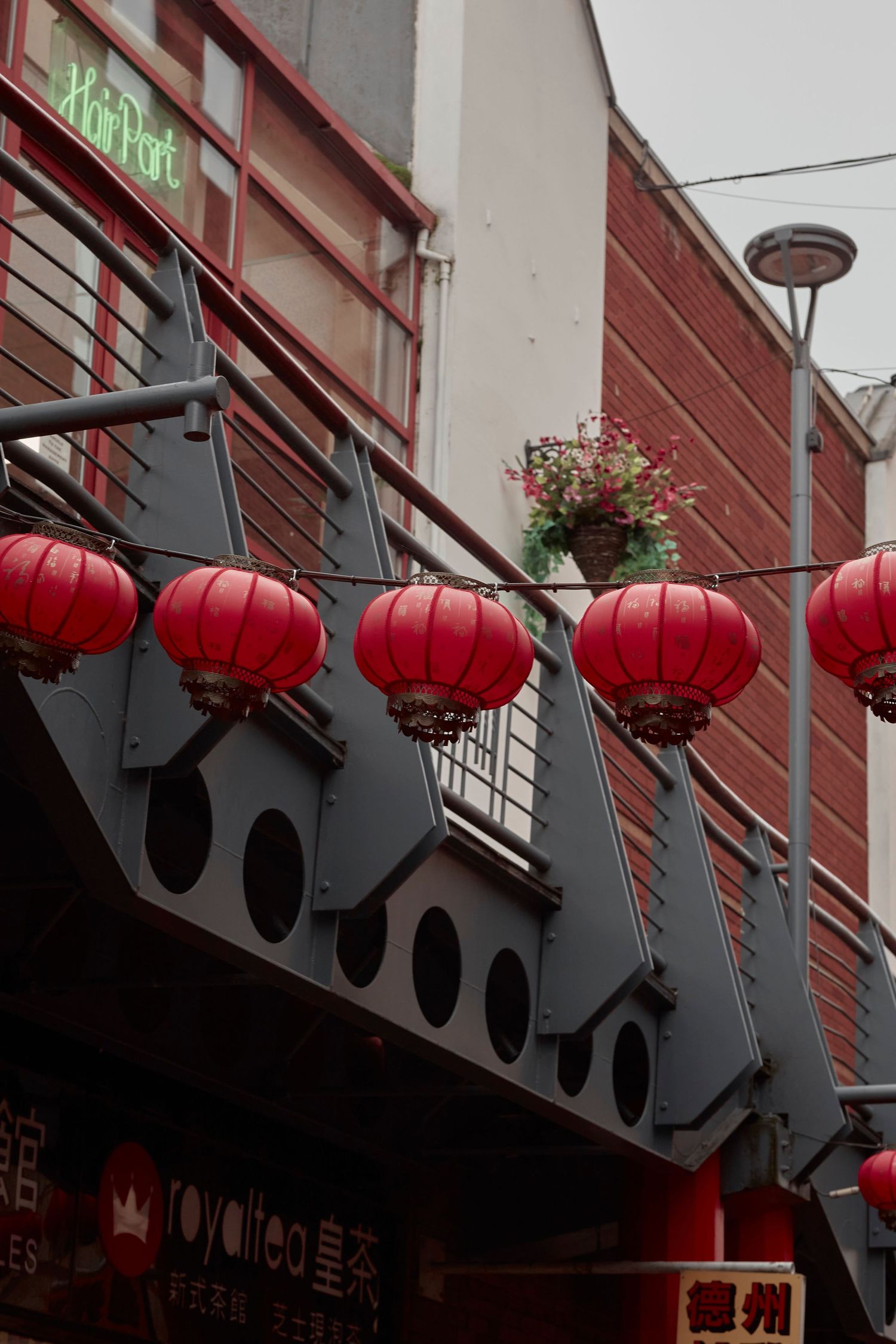 Red Chinese lanterns hanging from a dark metal architectural detail on a building.
