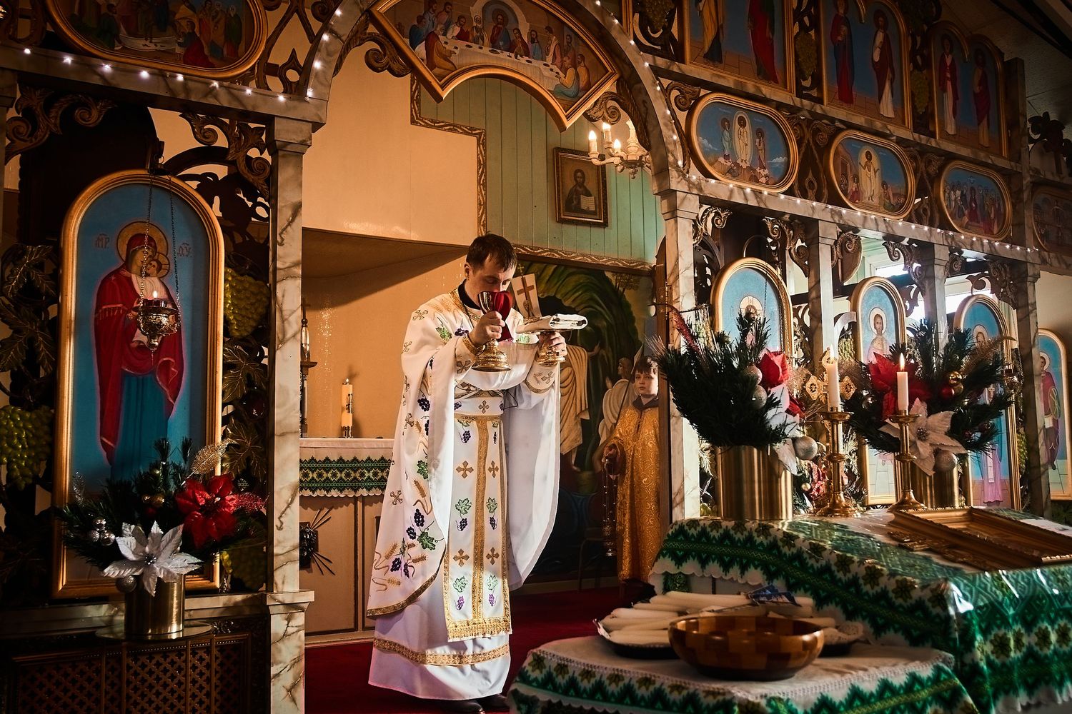 Orthodox church sanctuary with ornate iconostasis and seasonal decorations.