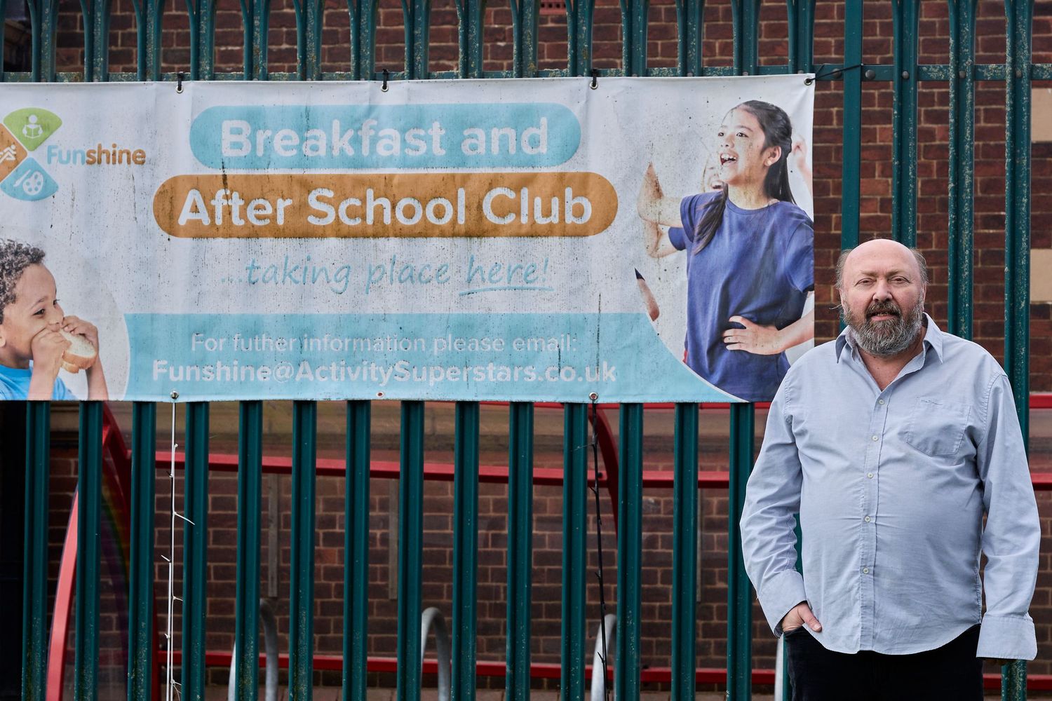 Person gesturing while standing near After School Club and Breakfast Club signage.