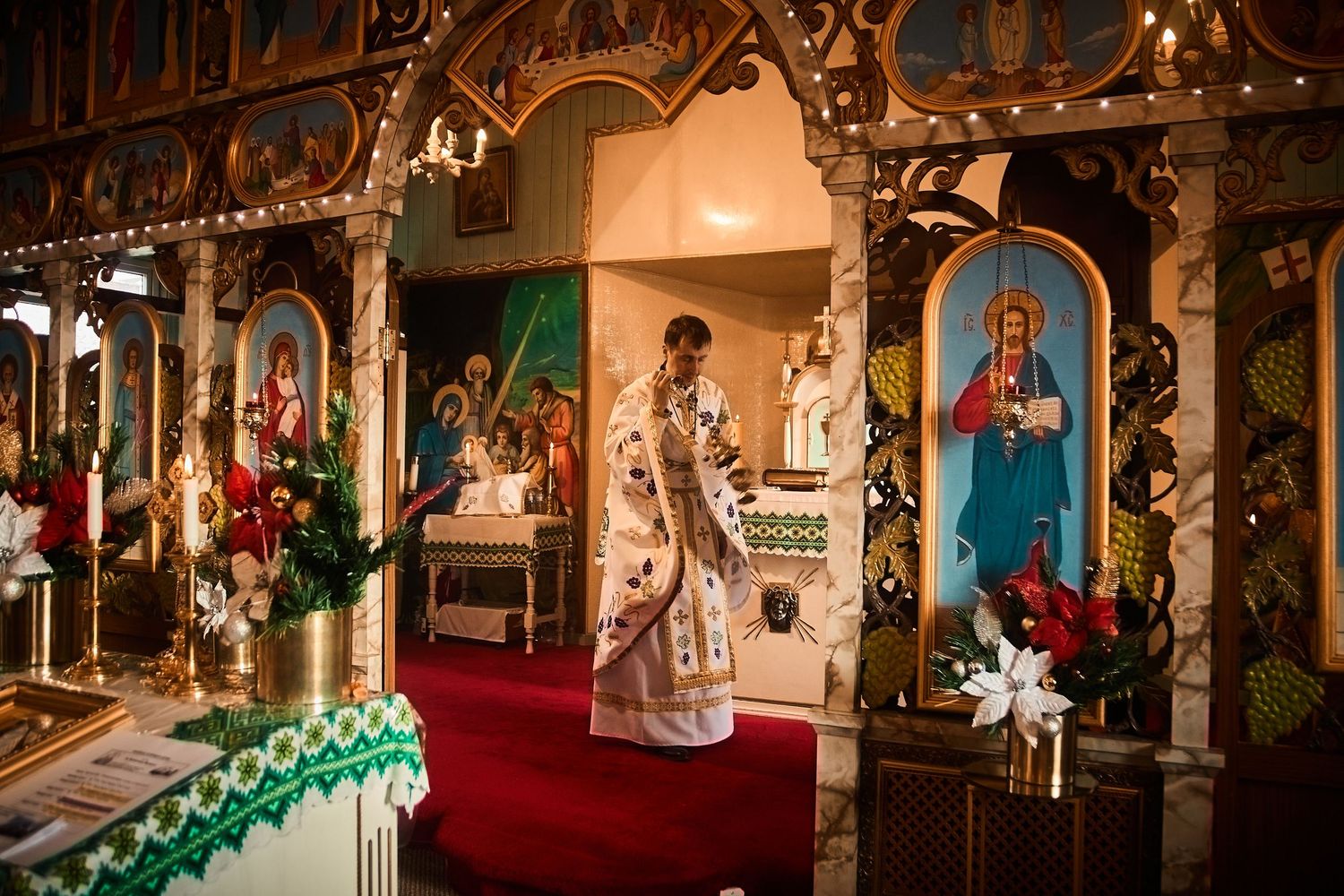Orthodox church sanctuary adorned with religious artwork and festive Christmas decorations.