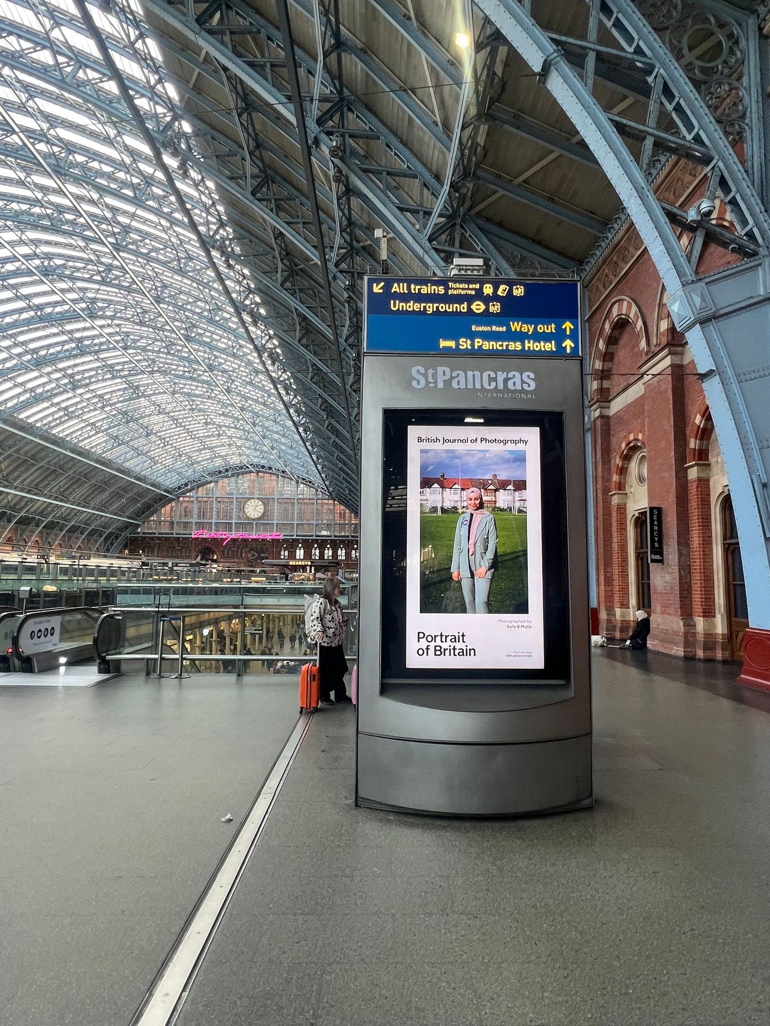 St Pancras station's architectural interior featuring digital advertising displays under curved glass roof.