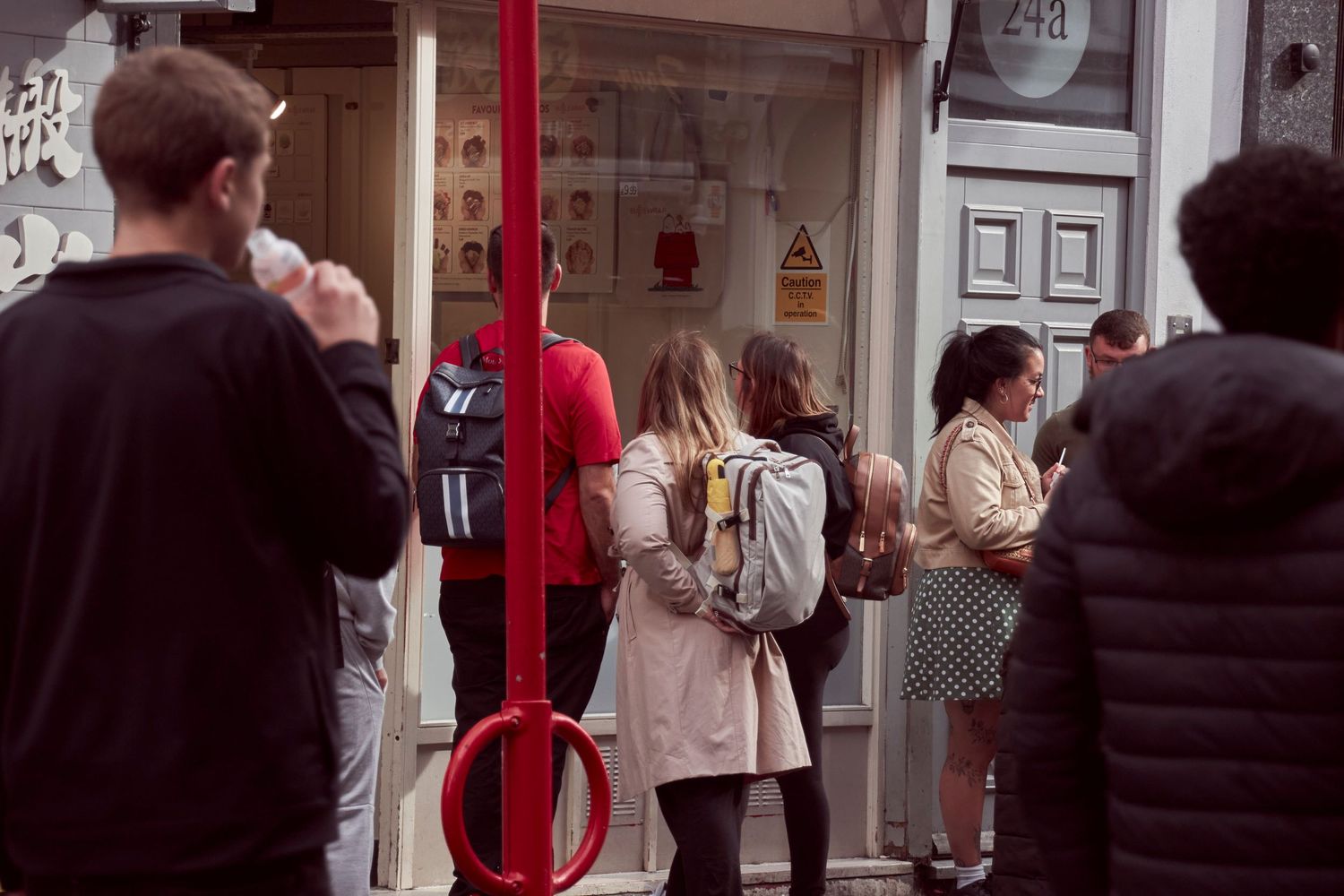 People queuing outside a restaurant in an urban setting.