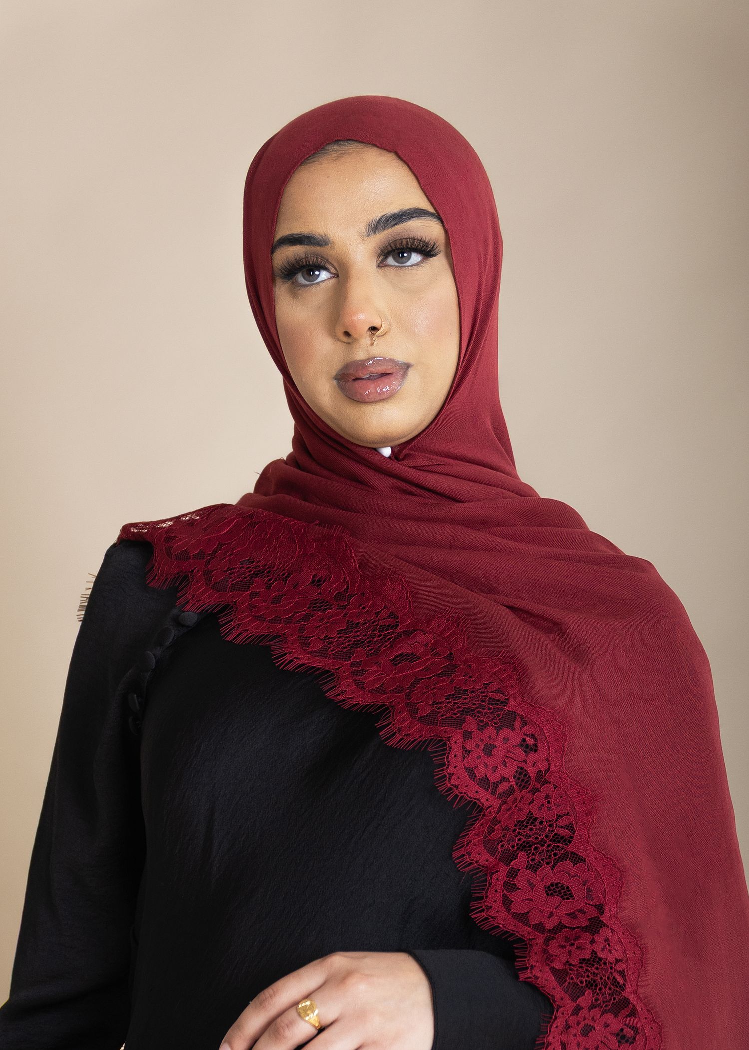 A series of photos showing a burgundy lace-trimmed hijab styled with a black outfit against a neutral background.
