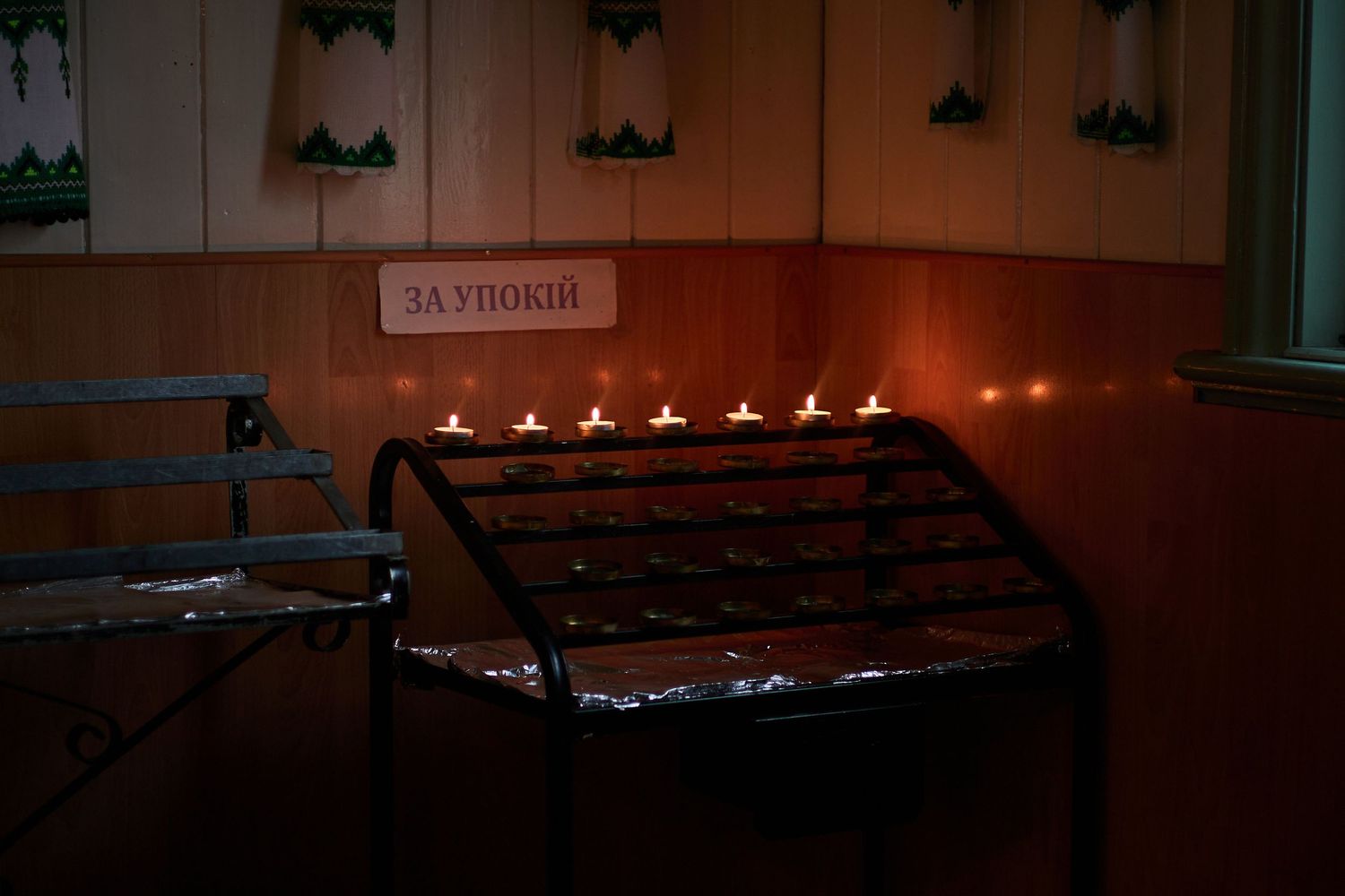 Row of glowing candles creating ambient lighting in a dark setting.