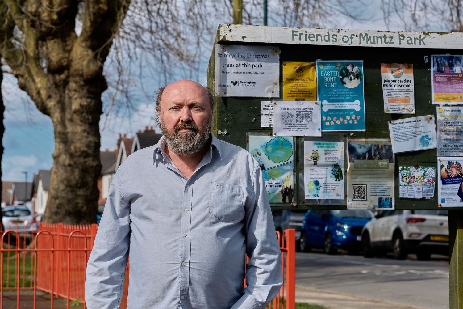 Community notice board displays colorful posters and flyers with person standing nearby.