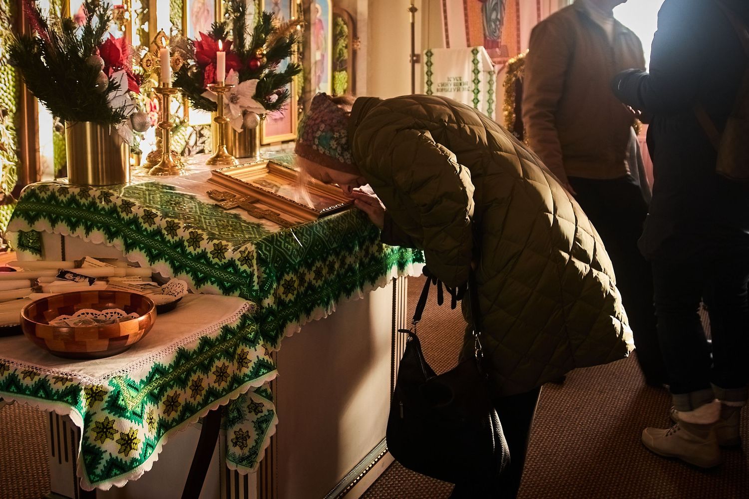 A candlelit church altar decorated with green garlands during a religious service.