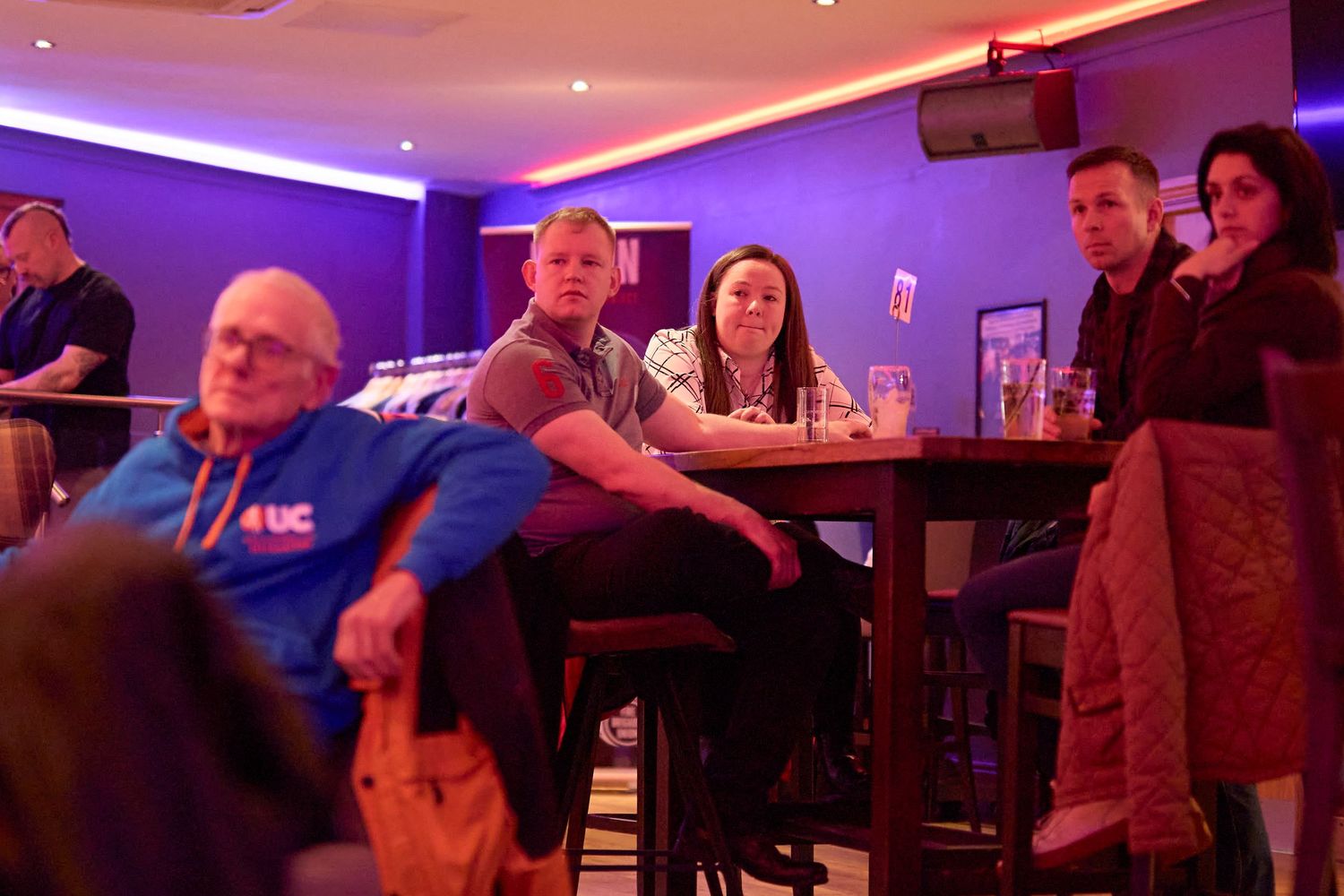 People enjoying a night out at a dimly lit bar with purple and red ambient lighting.