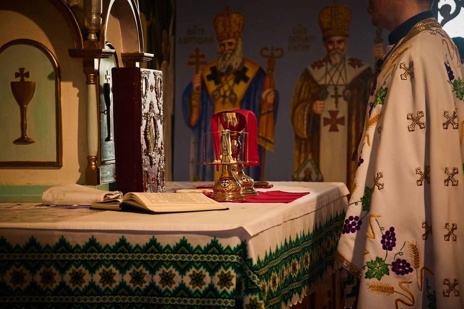 Orthodox altar with religious icons and golden chalice during church service.