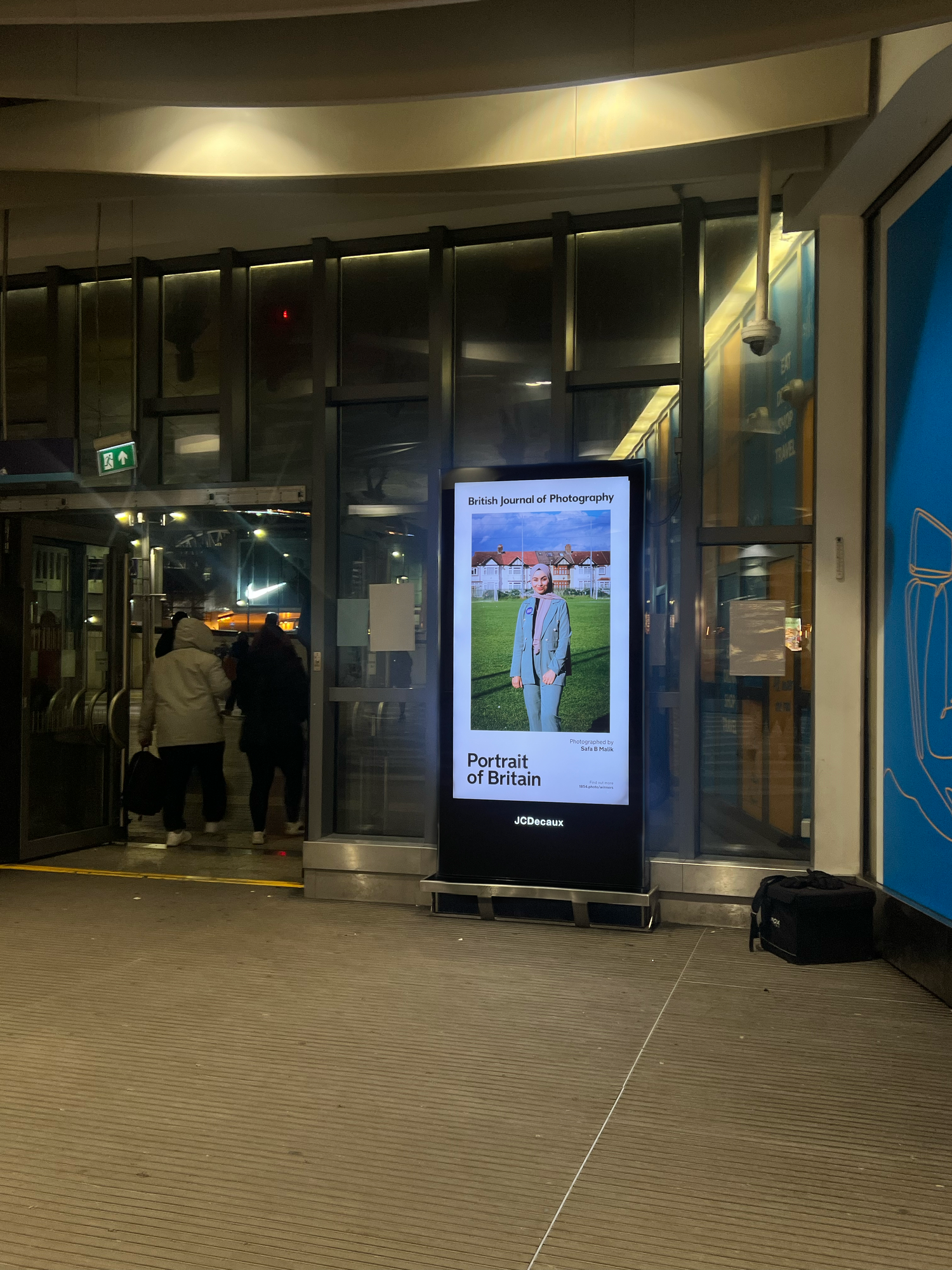 Empty indoor mall space with illuminated digital advertising displays showing photography exhibition.
