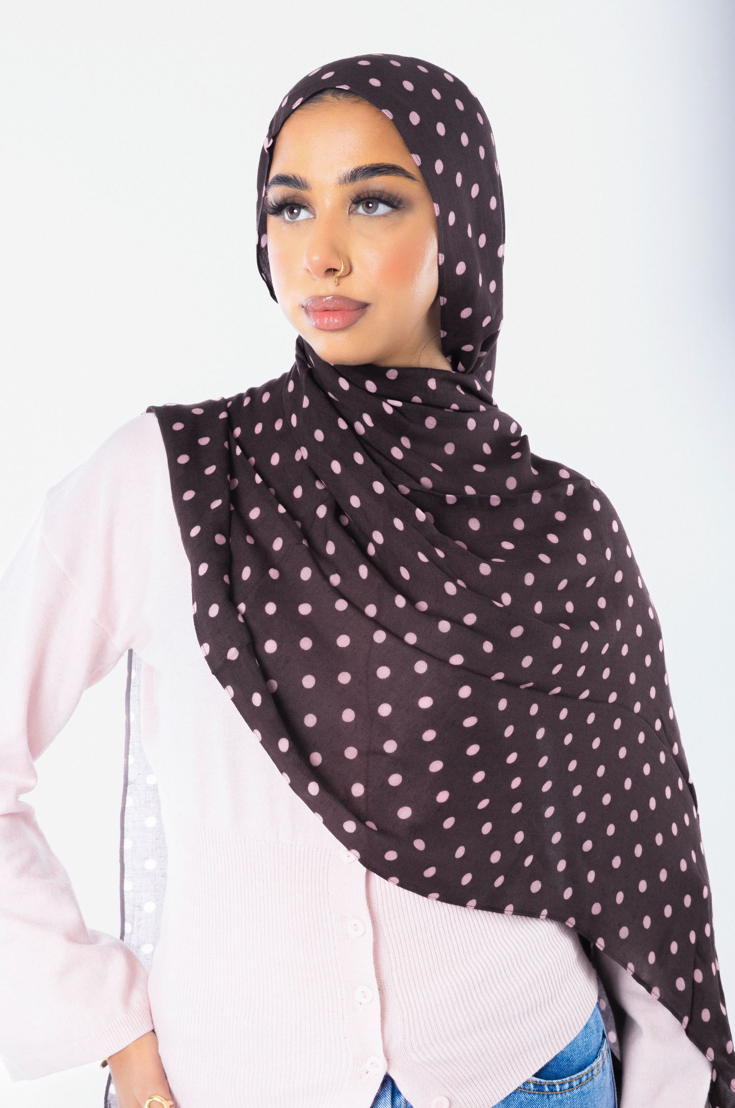 Woman wearing a dark brown polka dot hijab with pink dots, paired with a light pink button-up top.