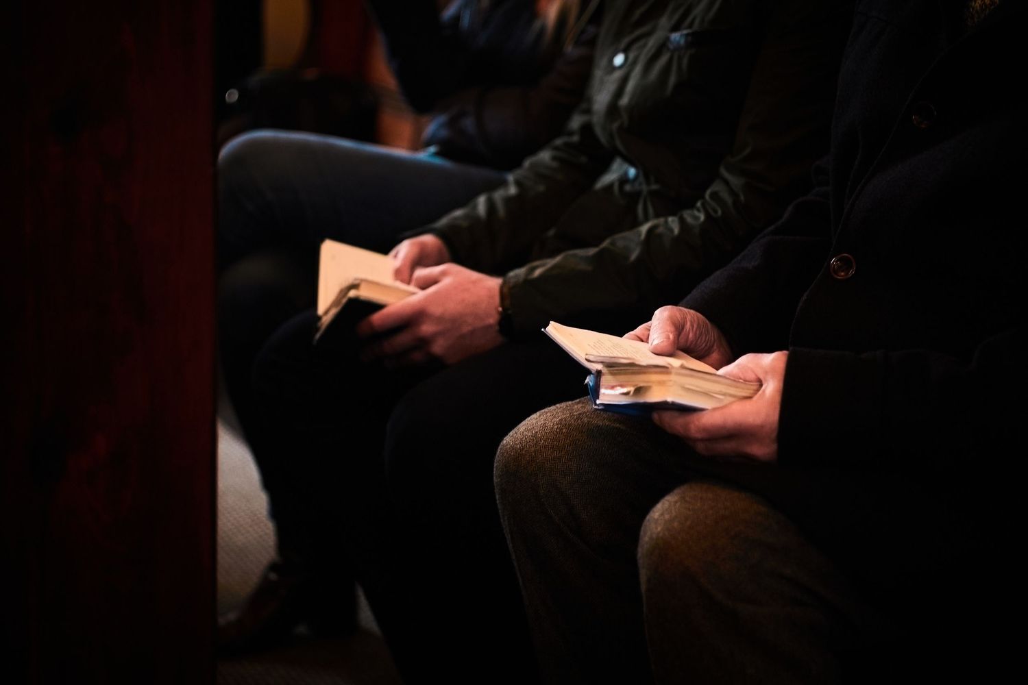 Close-up of hands holding prayer books during church service.