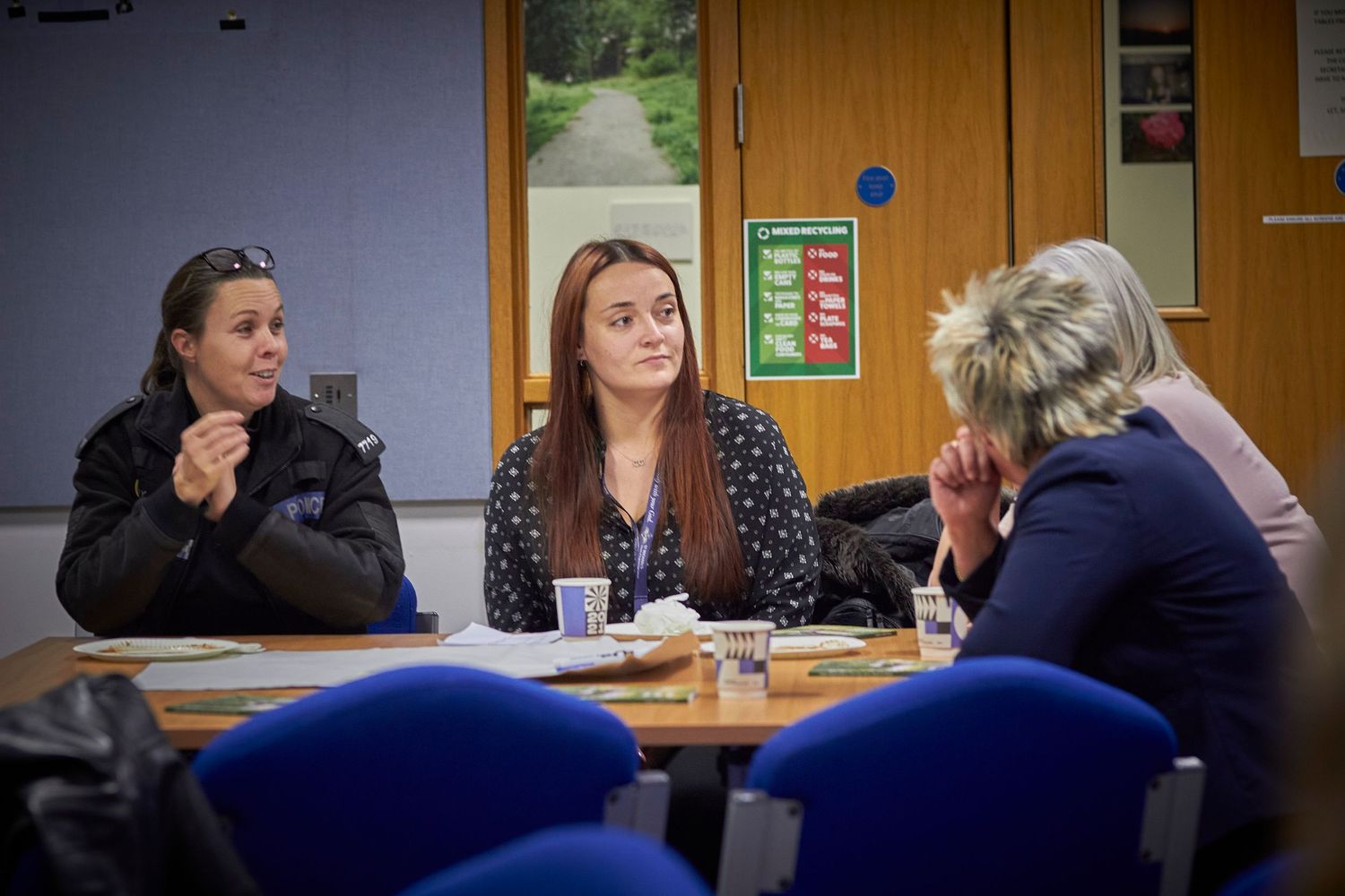 Three people sitting at a table during what appears to be an informal business meeting in an office environment.