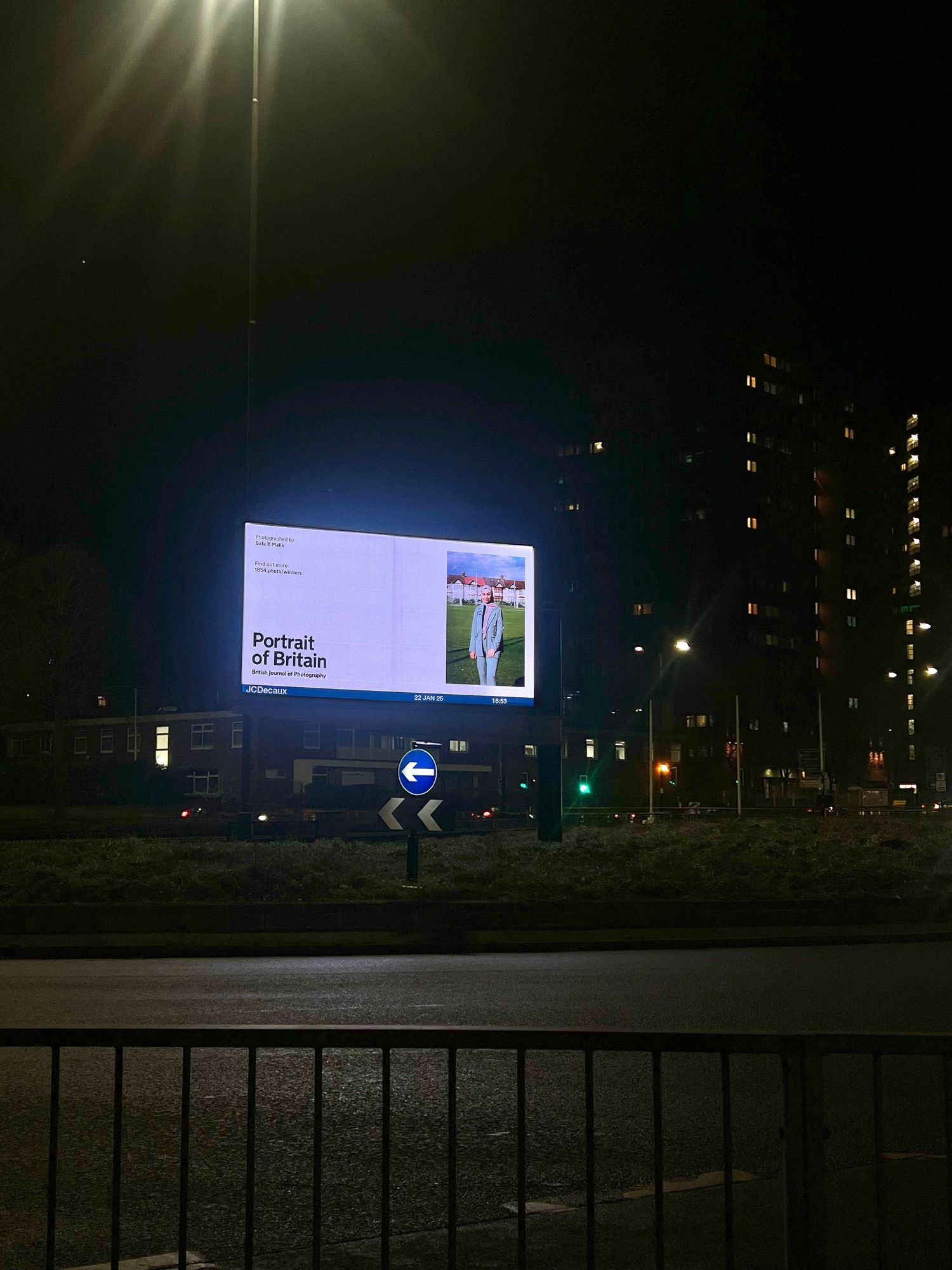 Large illuminated digital billboard display glowing at night with high-rise buildings visible in the background.