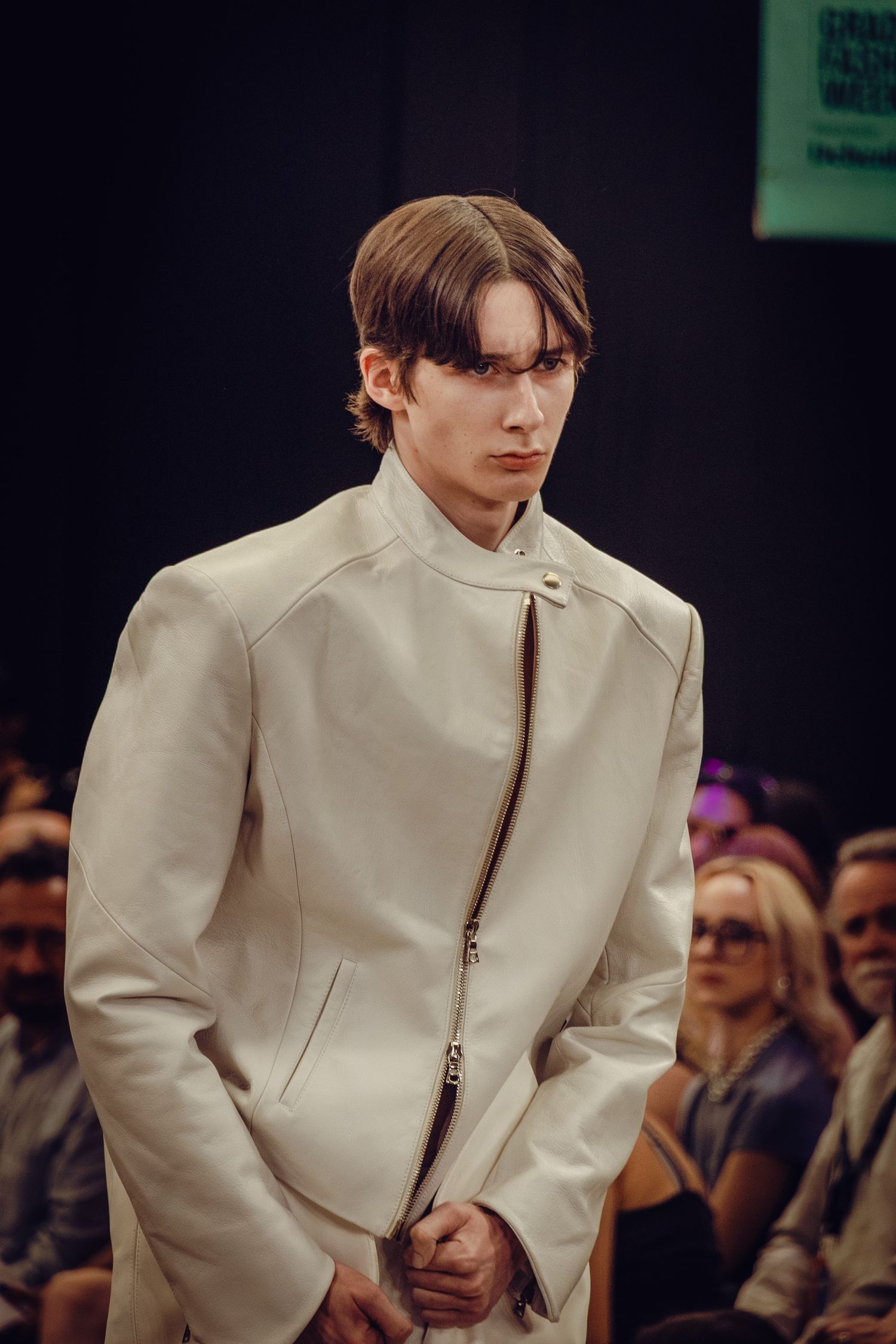 Minimalist cream colored structured jacket showcased on fashion runway.
