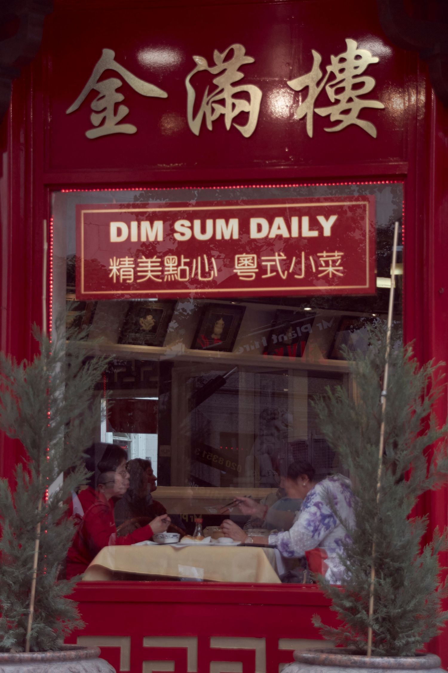 Dim sum restaurant window with traditional Chinese characters and English text advertising daily service.