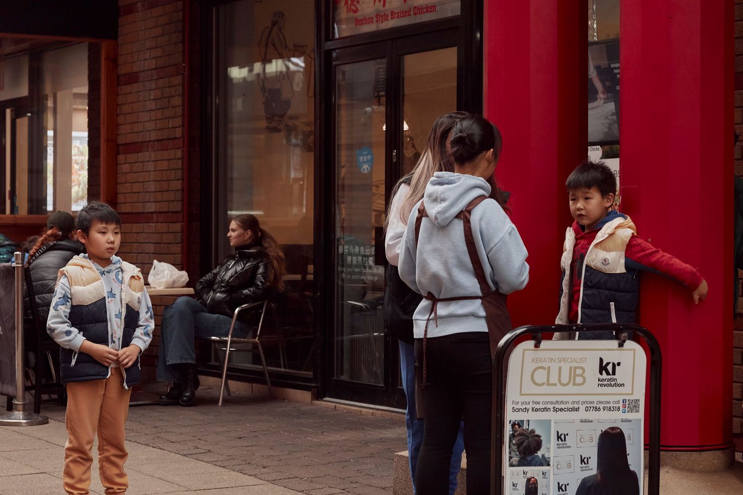 Group of people standing outside a storefront with red columns.