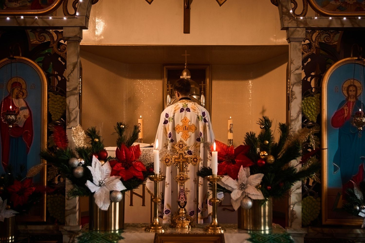 Orthodox church altar decorated with poinsettias, icons, and Christmas decorations.