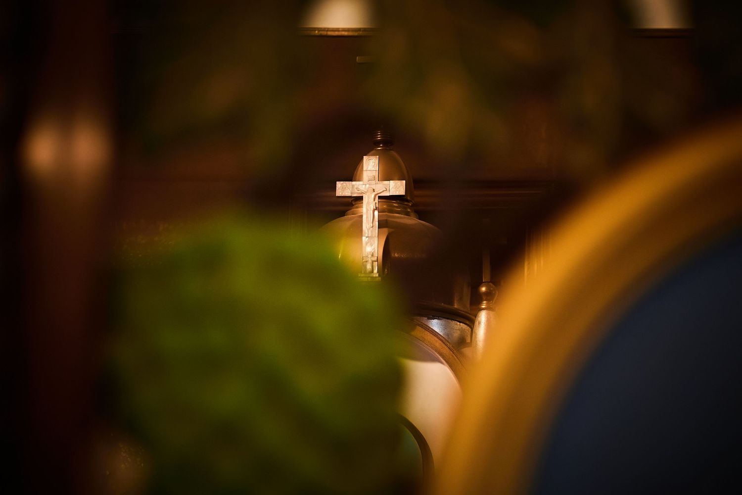 Illuminated cross in a dimly lit church setting creates a serene spiritual atmosphere.