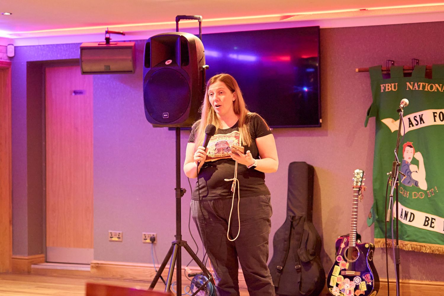 Colorful stage lighting illuminates a bar or venue setting with performance equipment and decor visible.