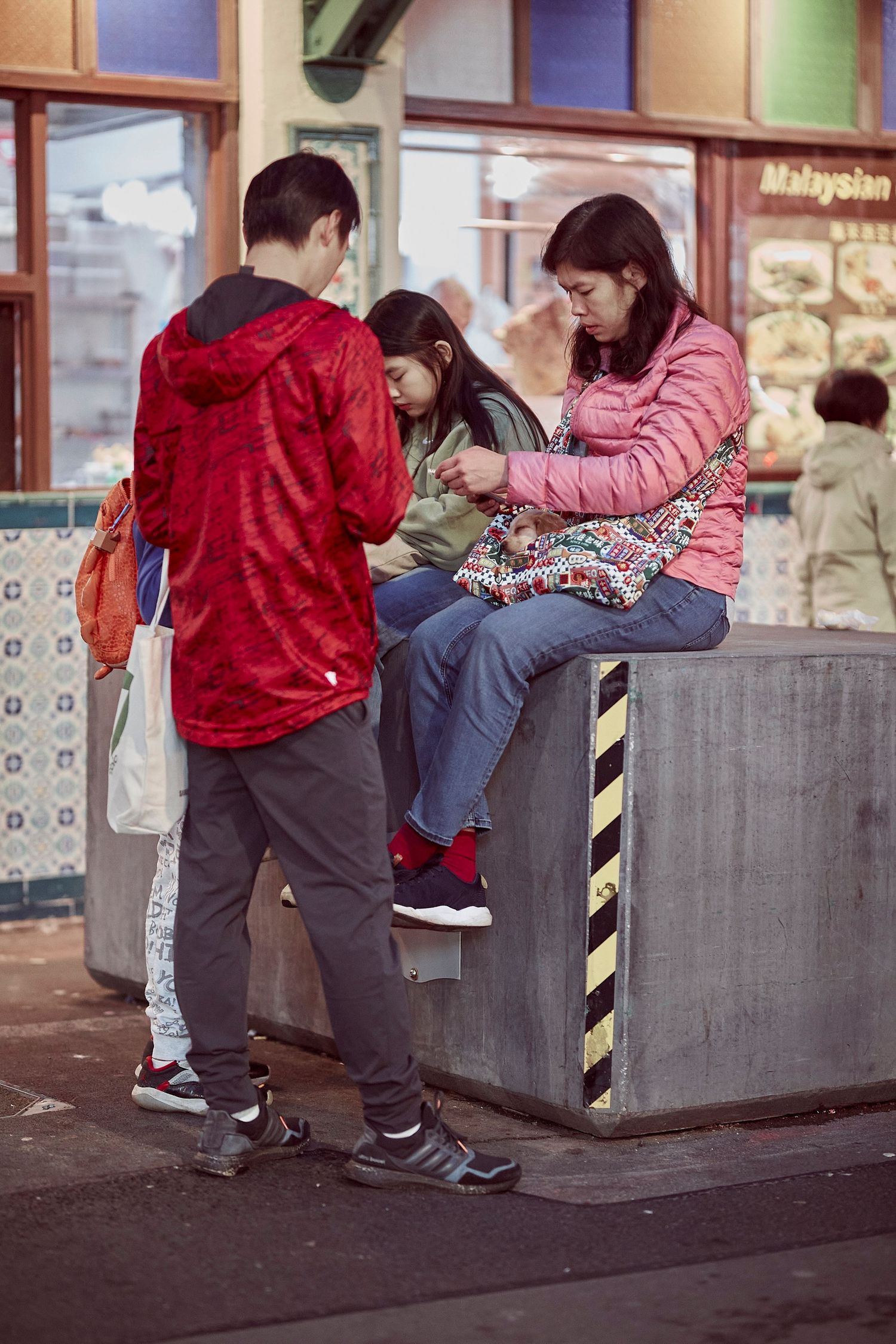 People gathering at an urban street corner near retail storefronts.