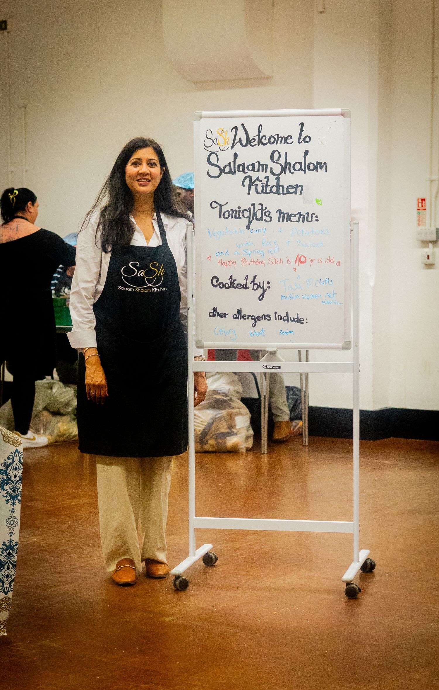 Mobile whiteboard displays welcome message in a room with terracotta floors.