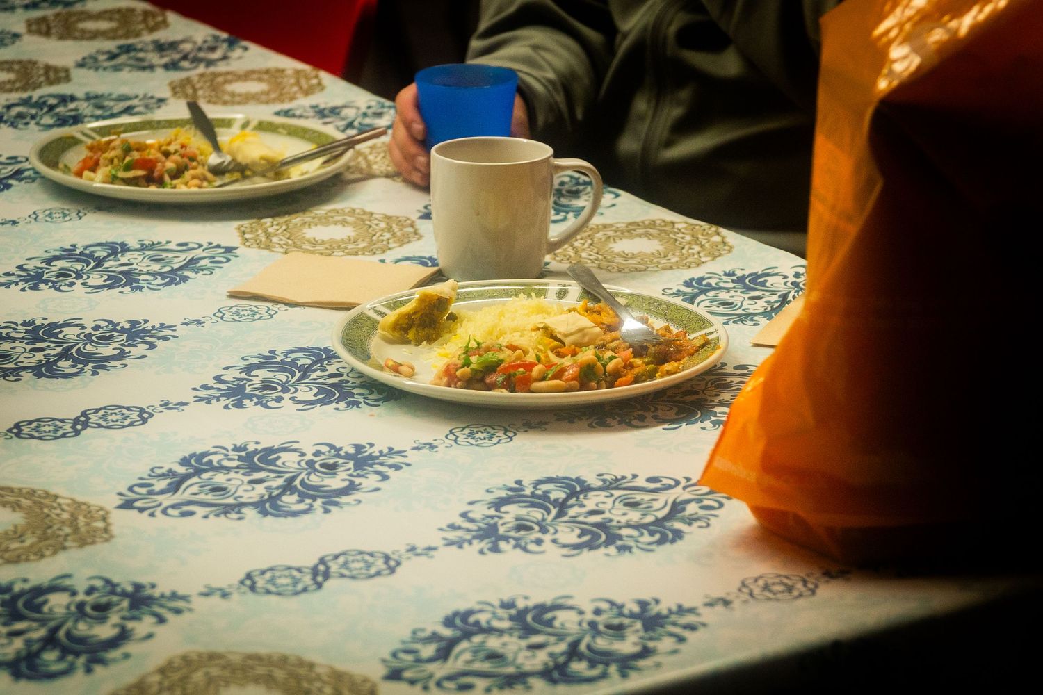 A table set with blue and white patterned cloth displays plates of food and coffee cups.