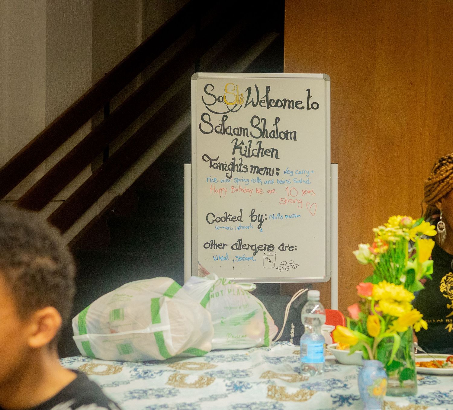 A handwritten sign for San Francisco Kitchen is displayed near yellow flowers.