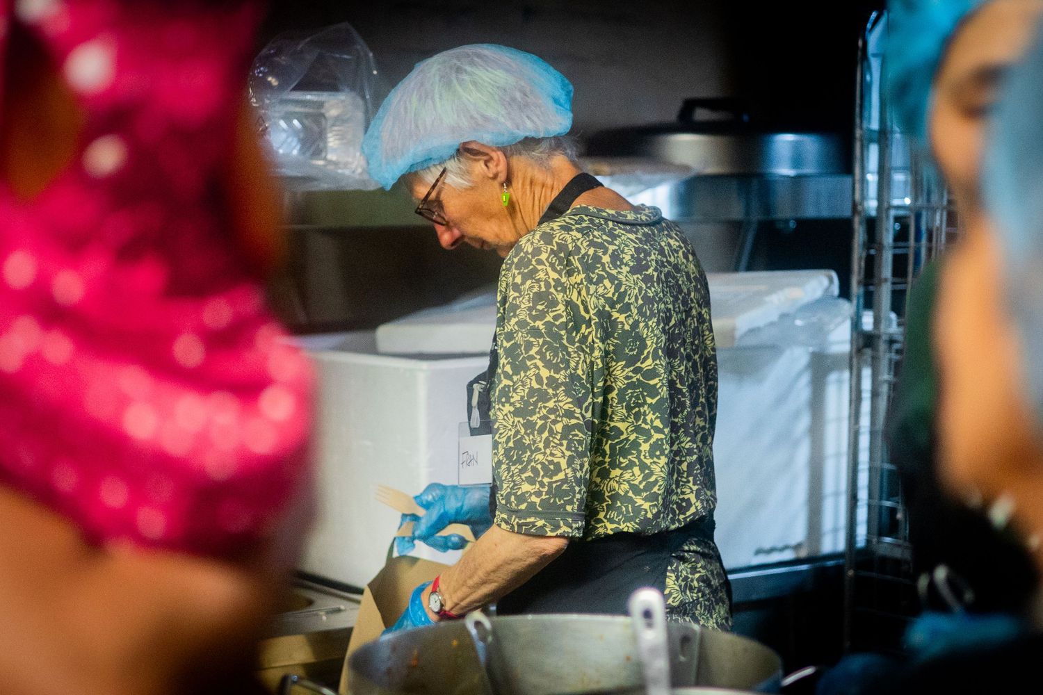 Commercial kitchen scene with food preparation equipment and staff working.