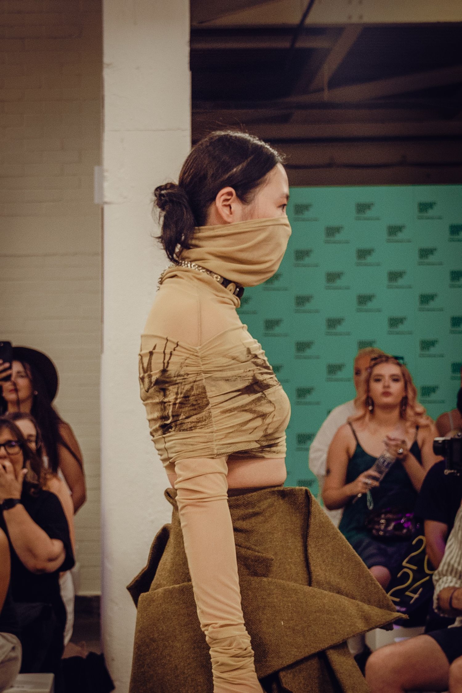 Fashion model showcases avant-garde beige wrapped design on catwalk at Debenhams Graduate Fashion Week.