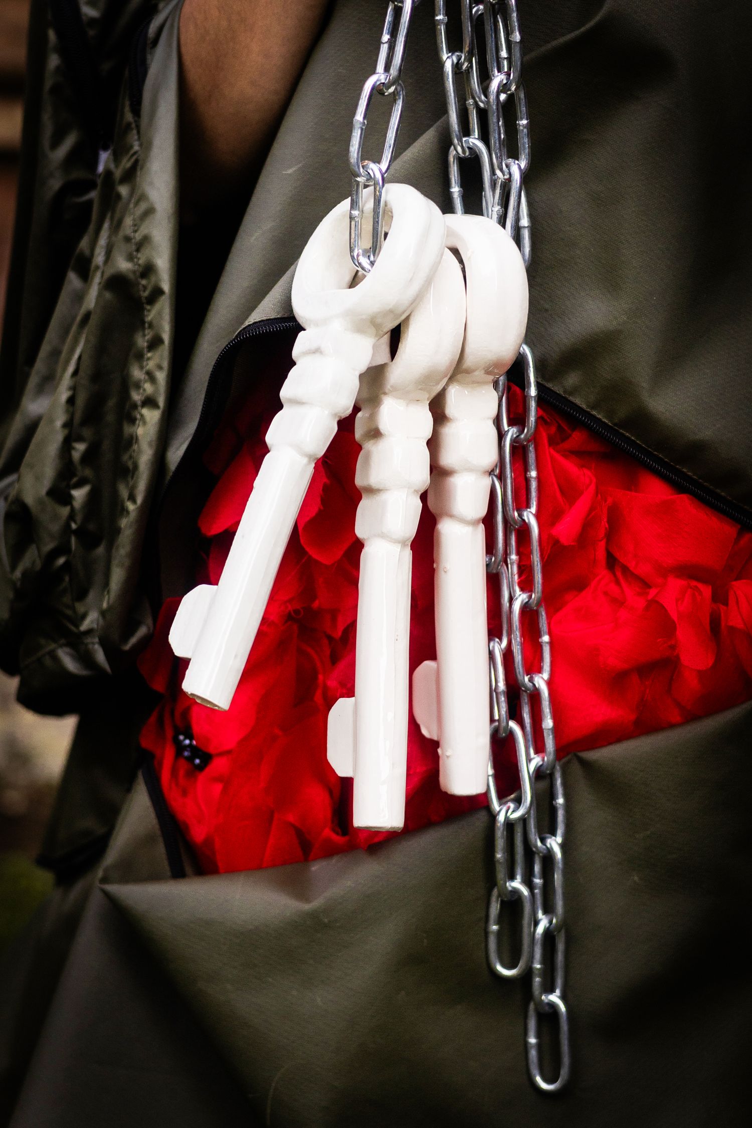 White skeleton hands dangle from metal chains against a dramatic red and black background.