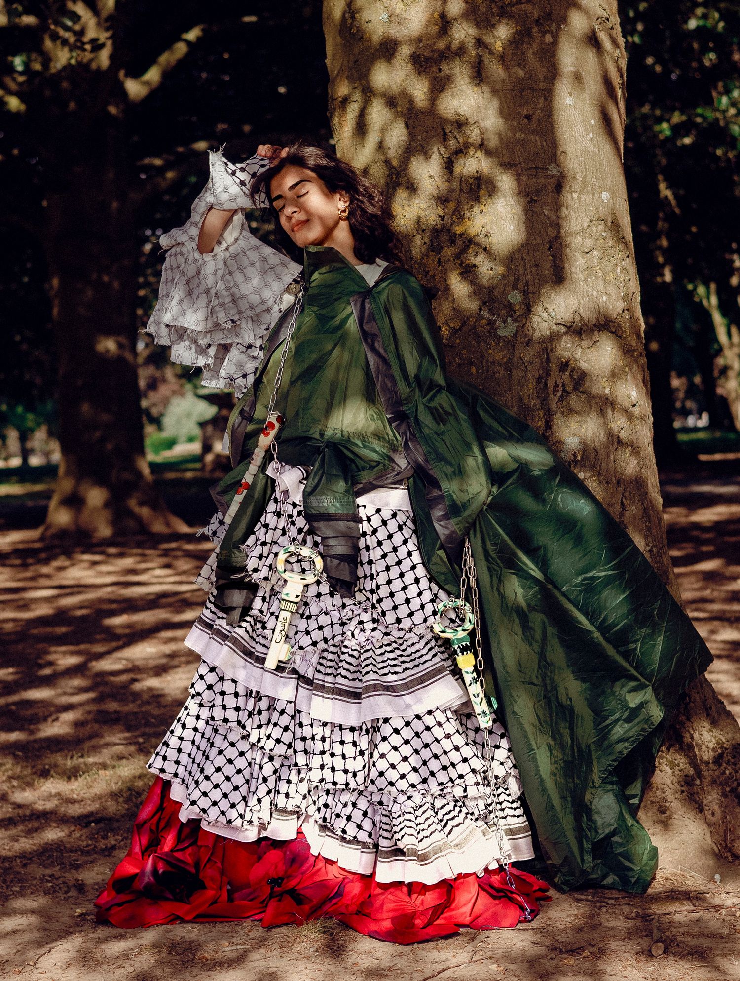 Vintage style photograph showing elaborate Civil War era dress with polka dot pattern, green cape, and red trim in dappled sunlight.