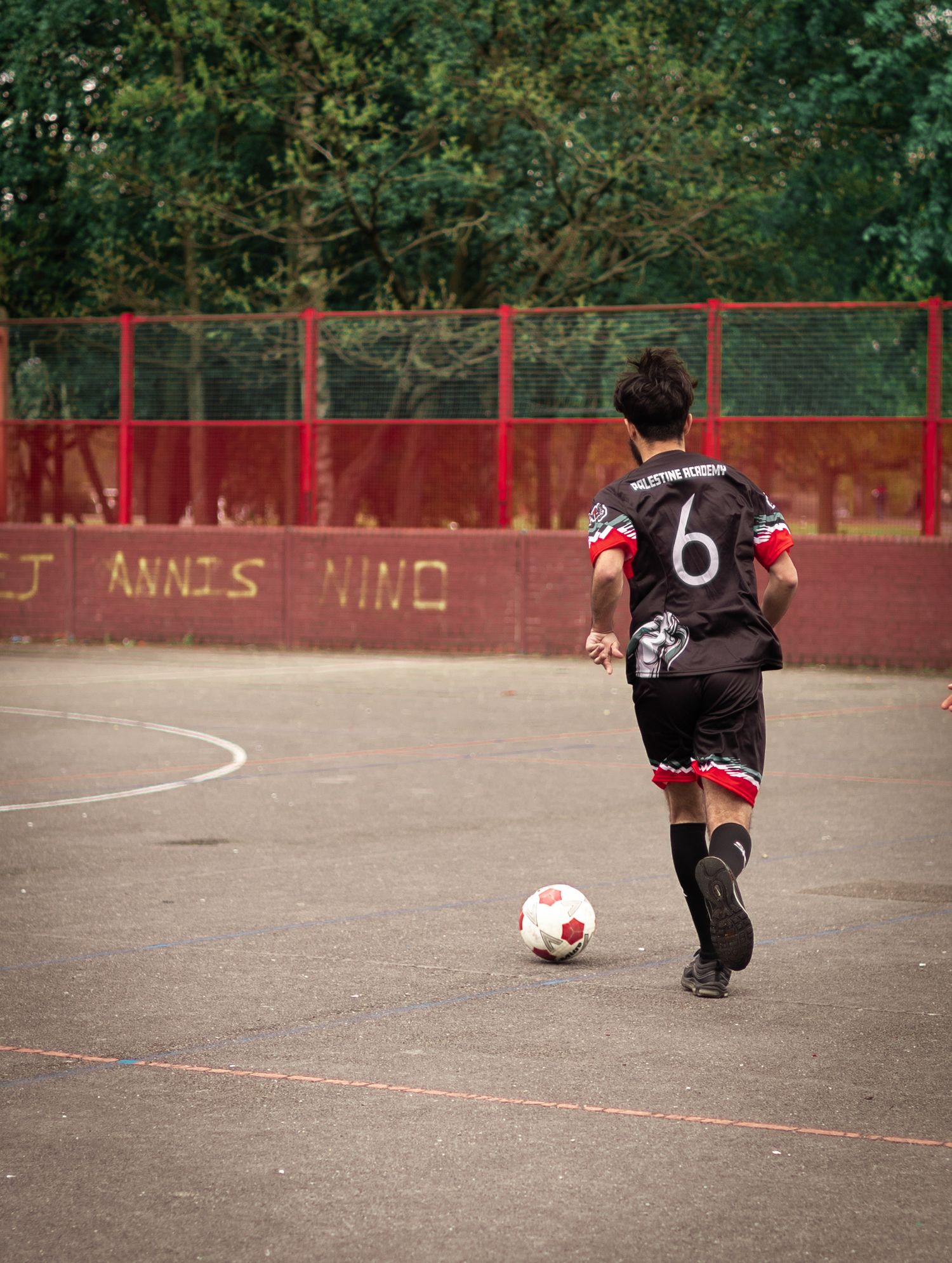 Soccer player wearing number 6 jersey runs with the ball on an outdoor court.