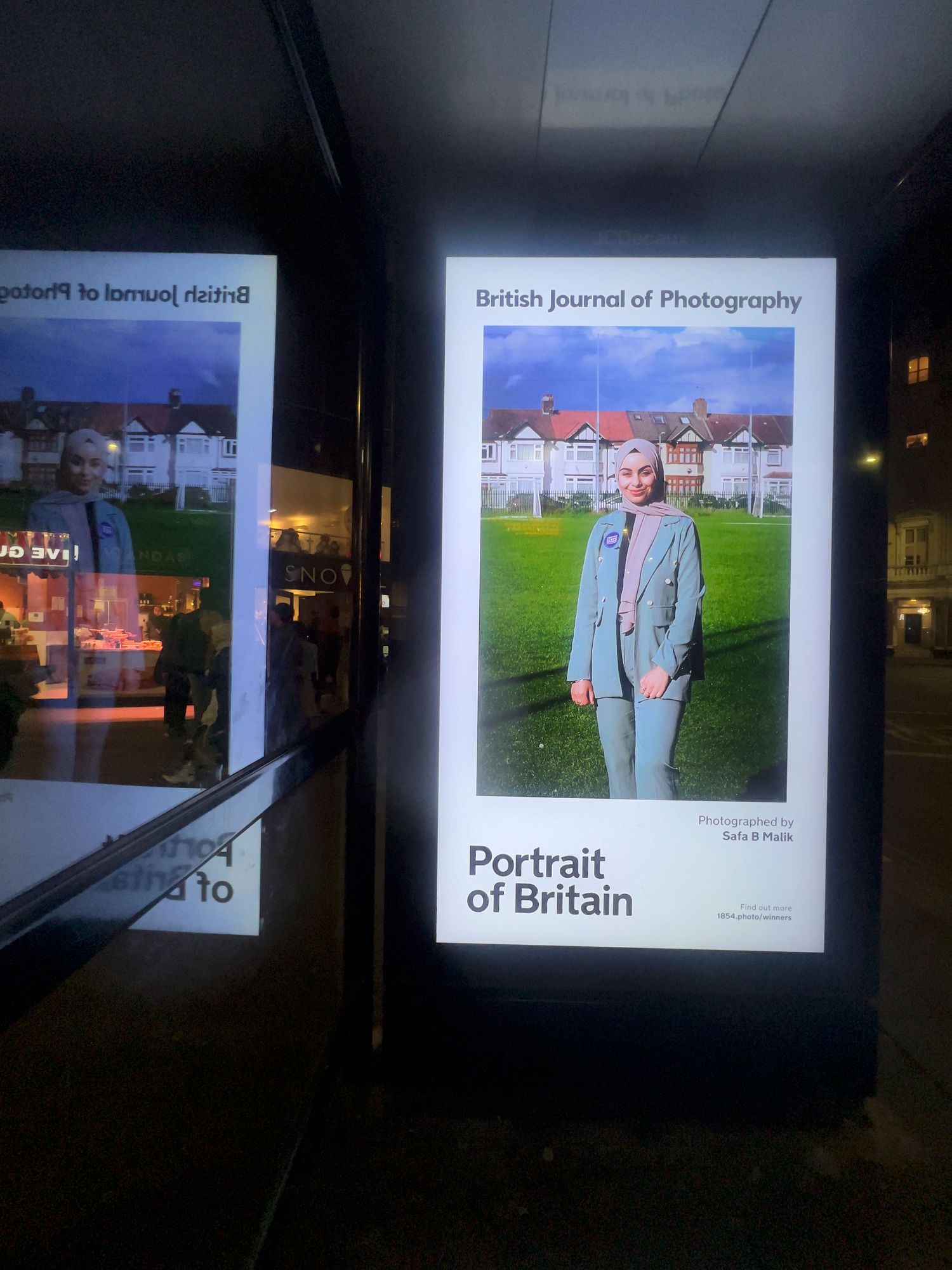 Night view of digital displays showing British Journal of Photography exhibition content.