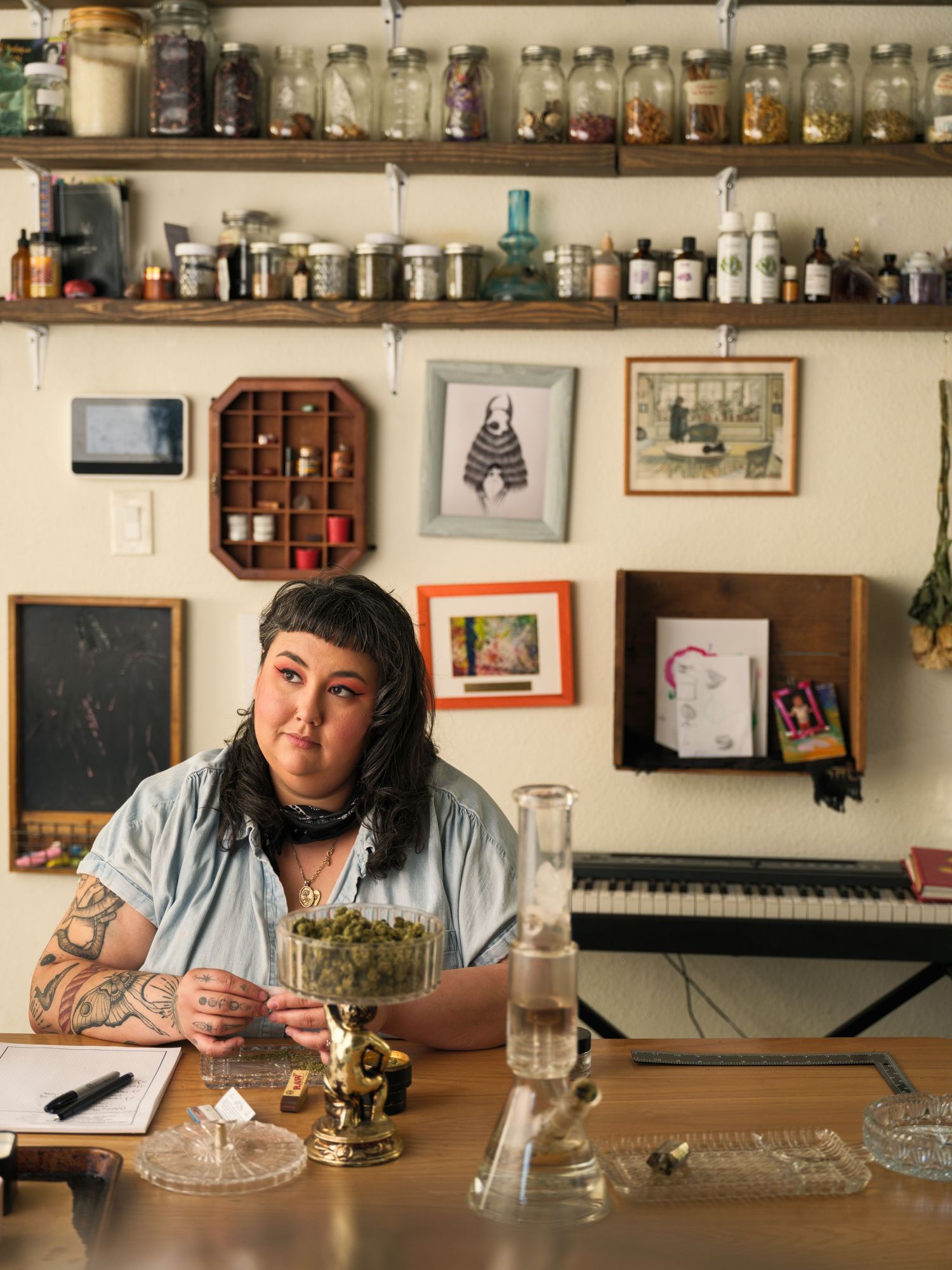 Person sitting at desk with collection of jars and bottles on shelves in background.